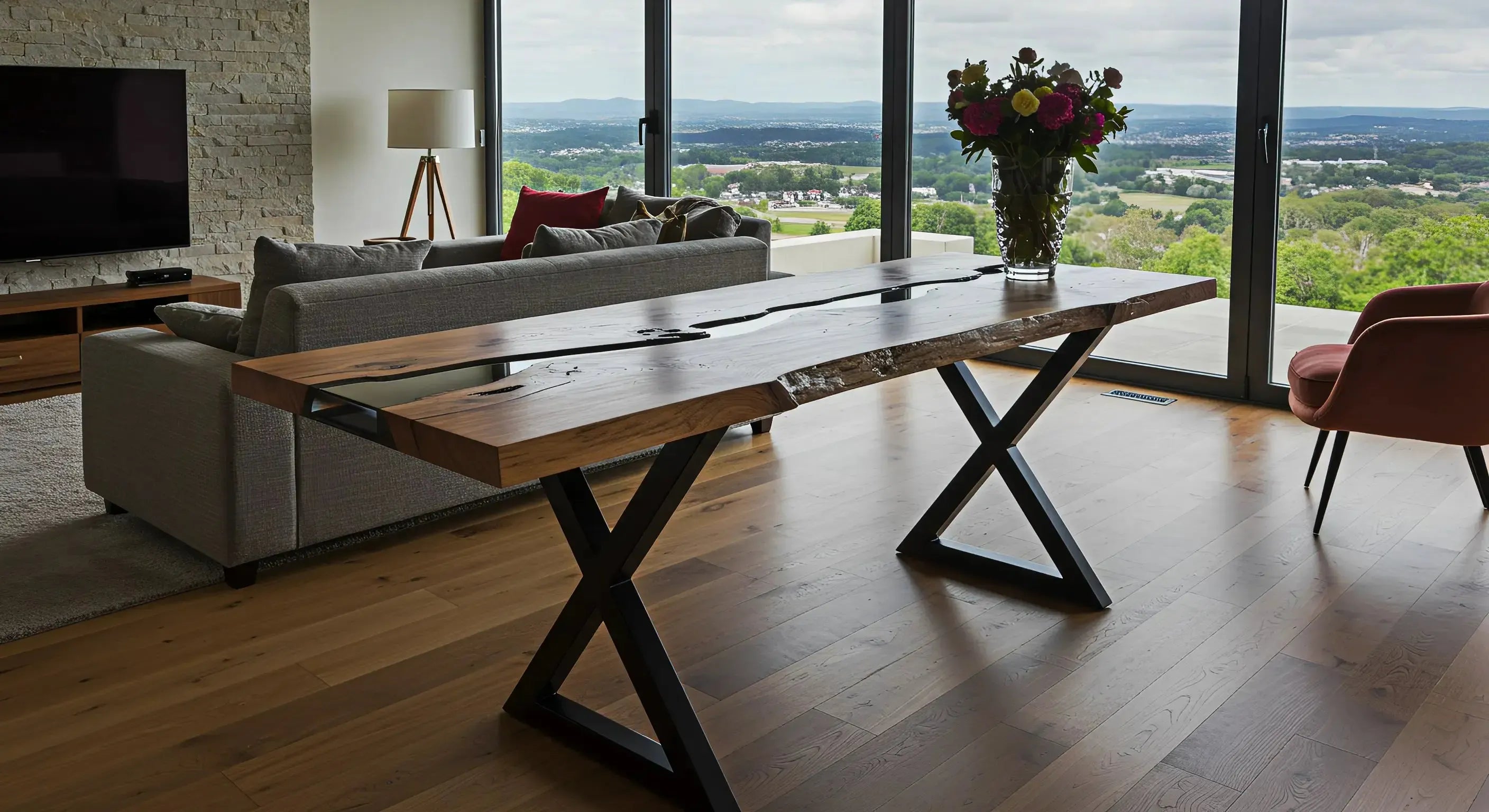 resin console table inside a luxury cabin with floor to ceiling windows and a view of the mountains. The epoxy console table has black resin, walnut wood, and x metal legs.