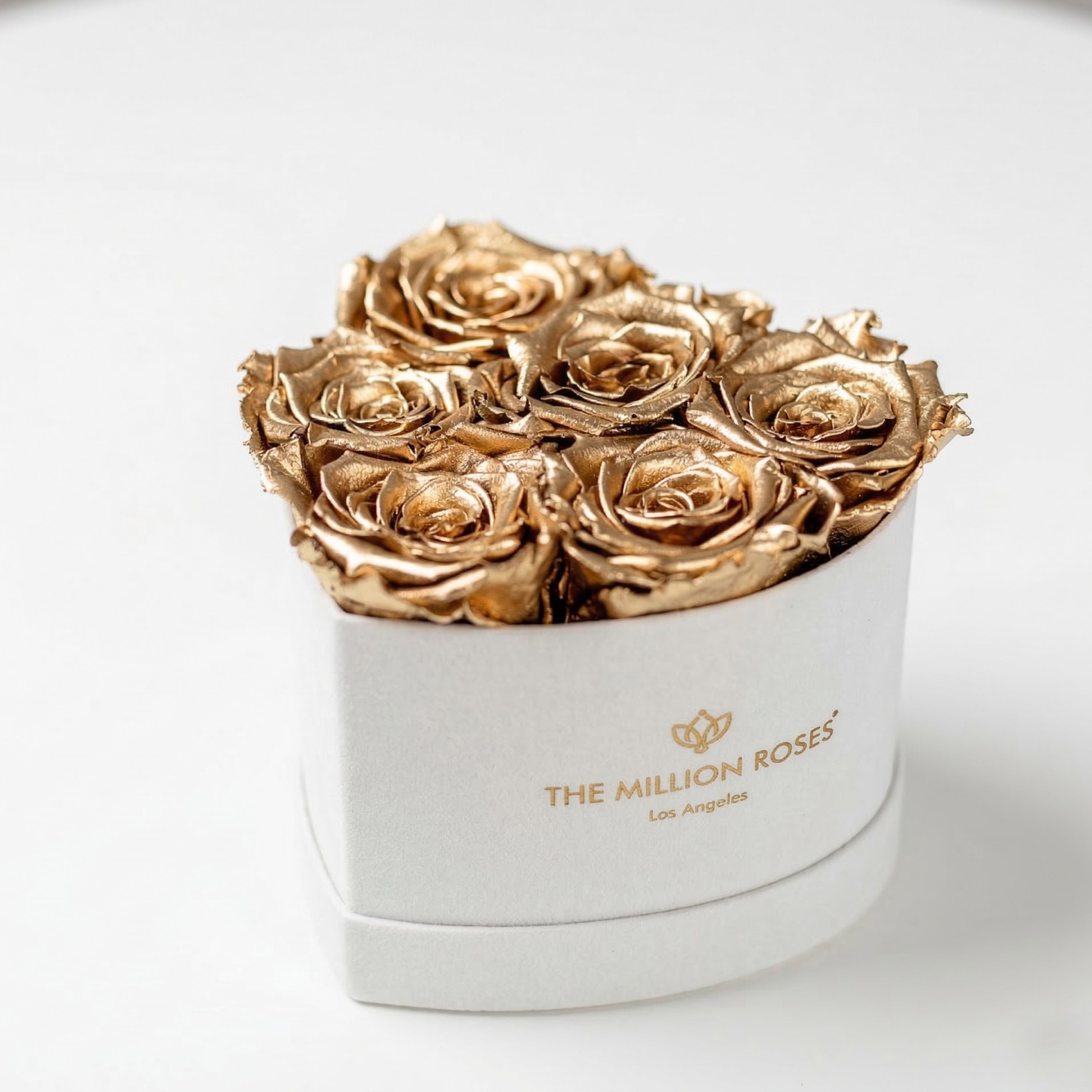 Beige suede box holding 6 gold roses shaped in a heart