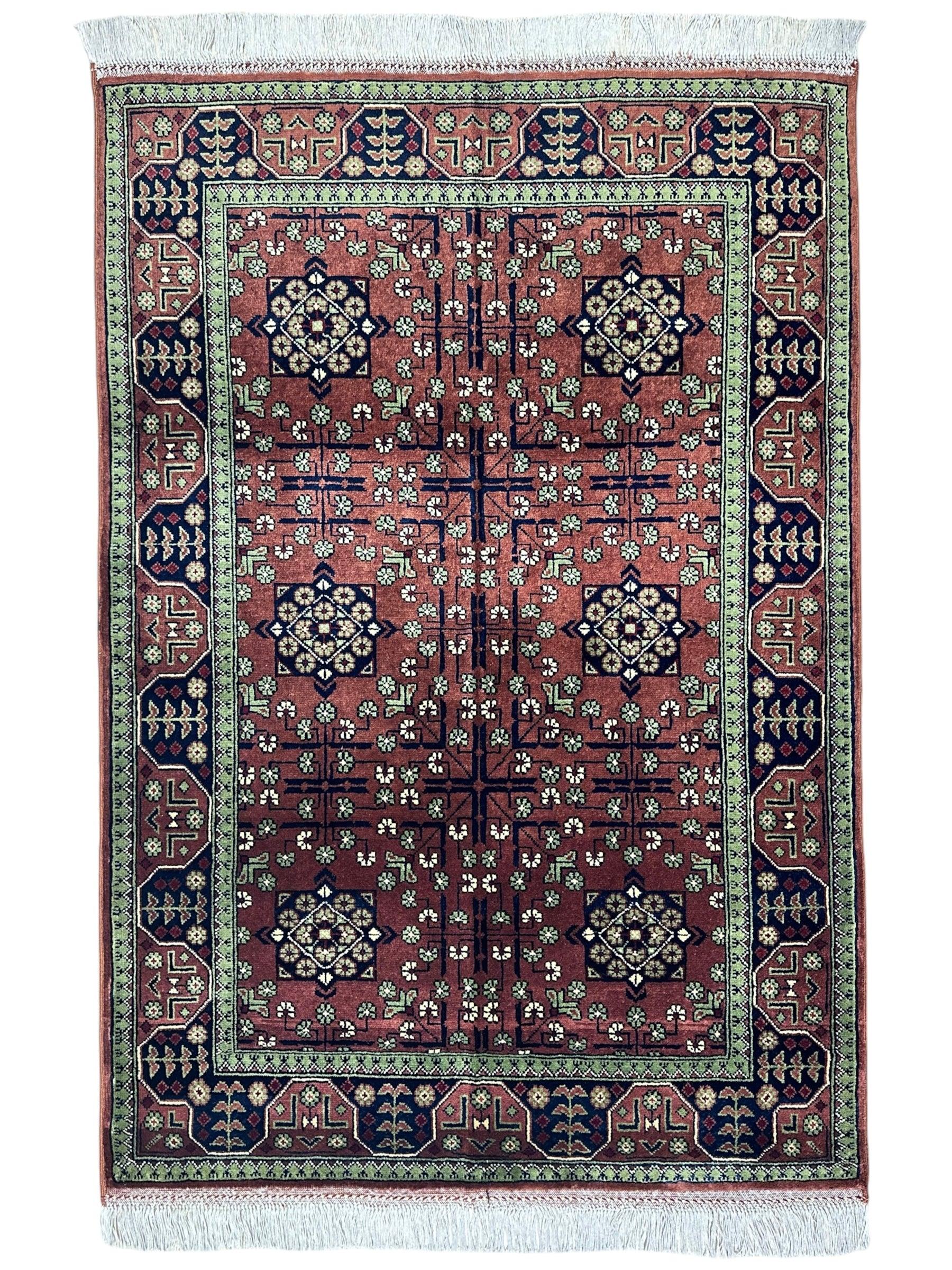 Hand-knotted Bukharayi rug in brown, deep red, ivory, and gold tones laid on floor