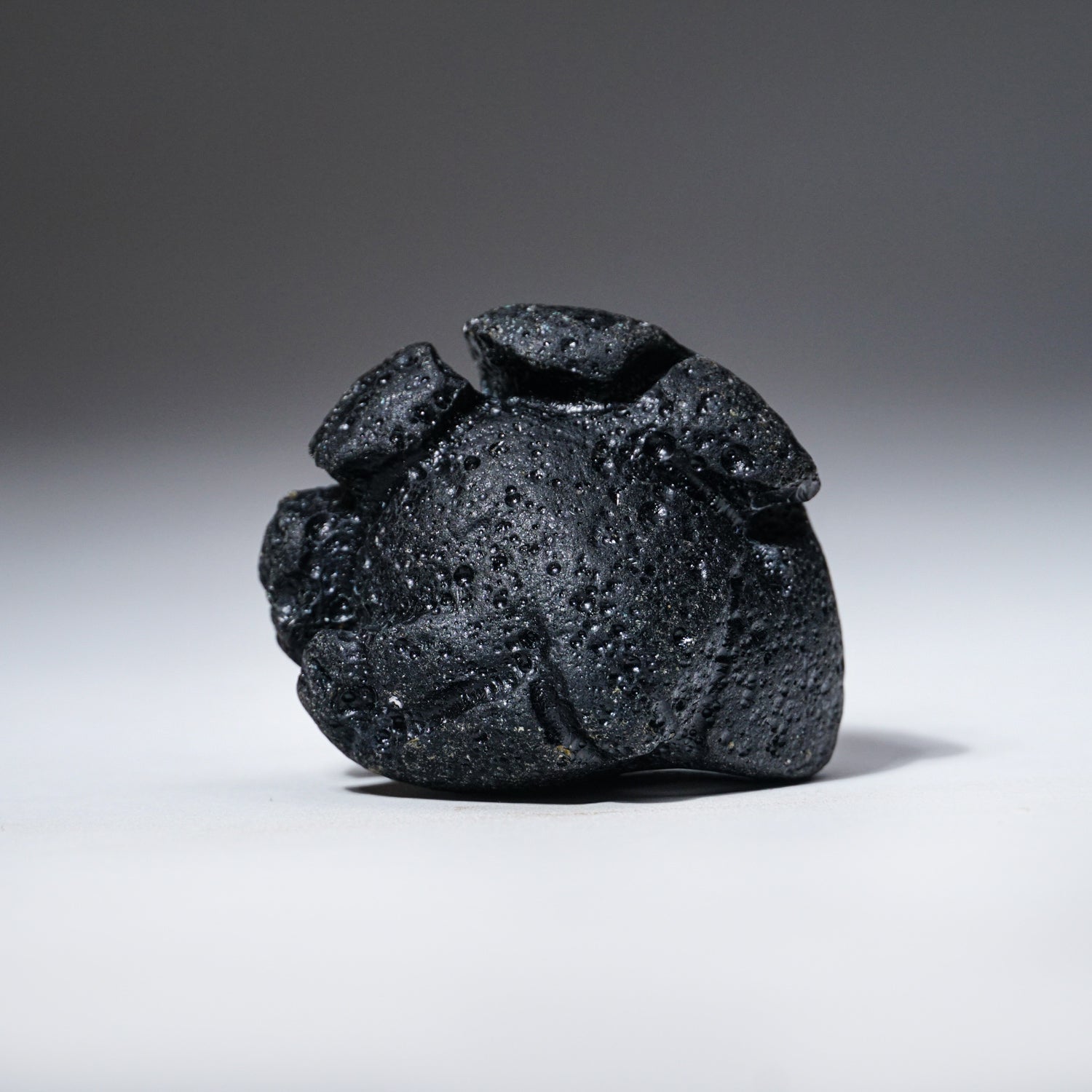 Genuine Indochinite Tektite specimen in display case on black stand