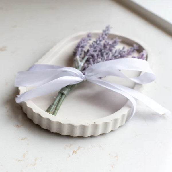 Heart-shaped dish with lavender and a white ribbon on a light surface