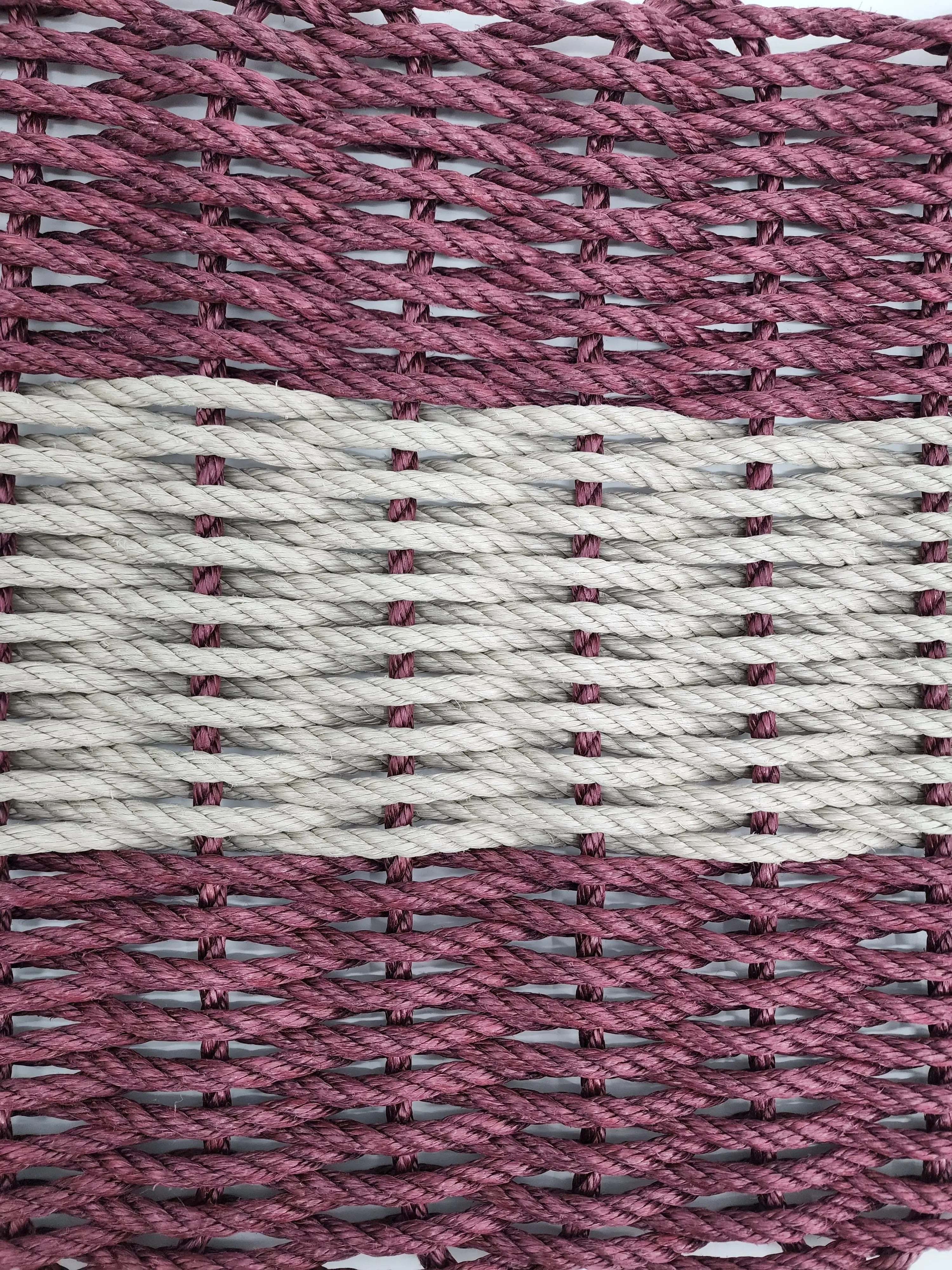 Burgundy and tan handmade lobster rope mat on wooden floor