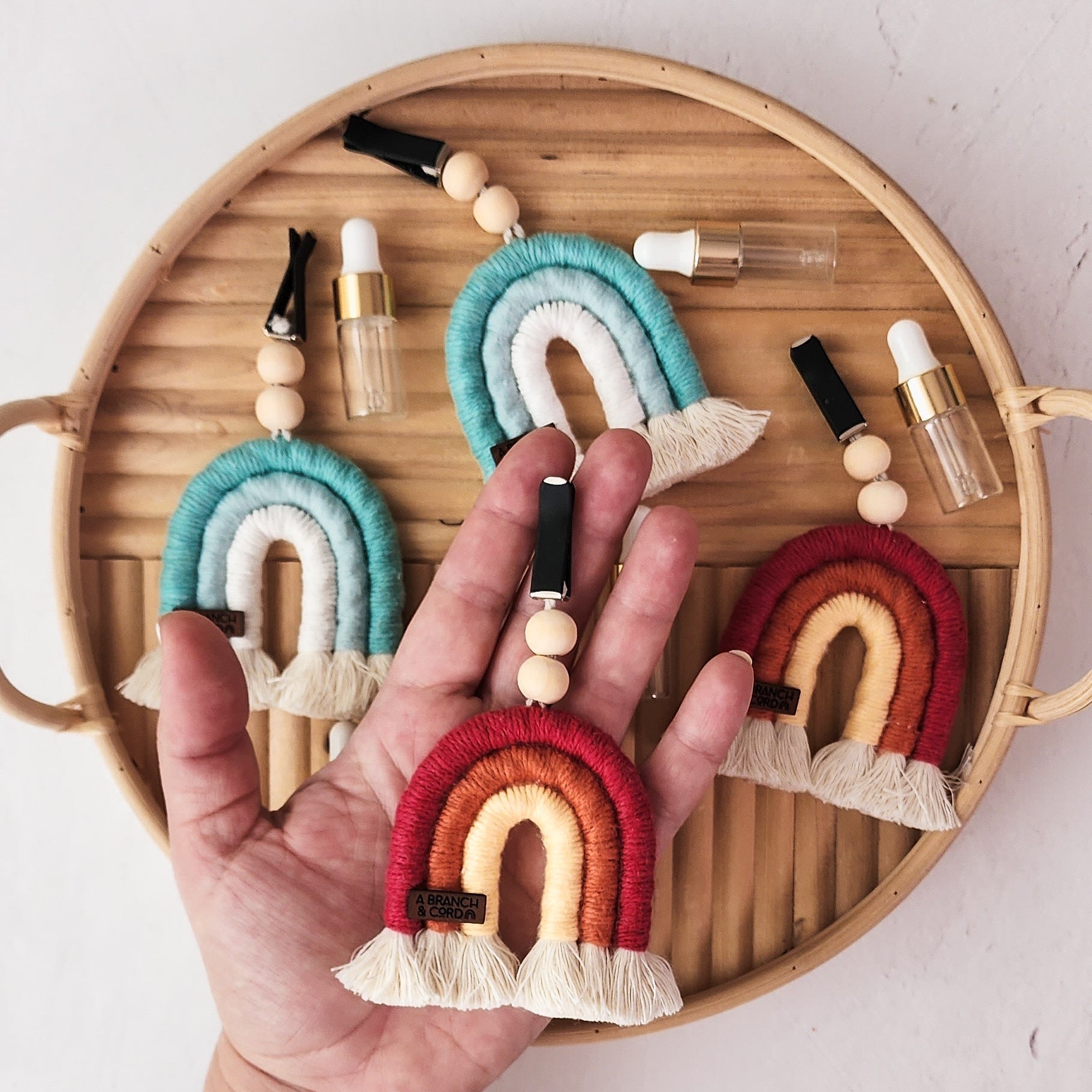 Macrame Car Vent Rainbow Diffuser hanging from a car vent in red and jade variations