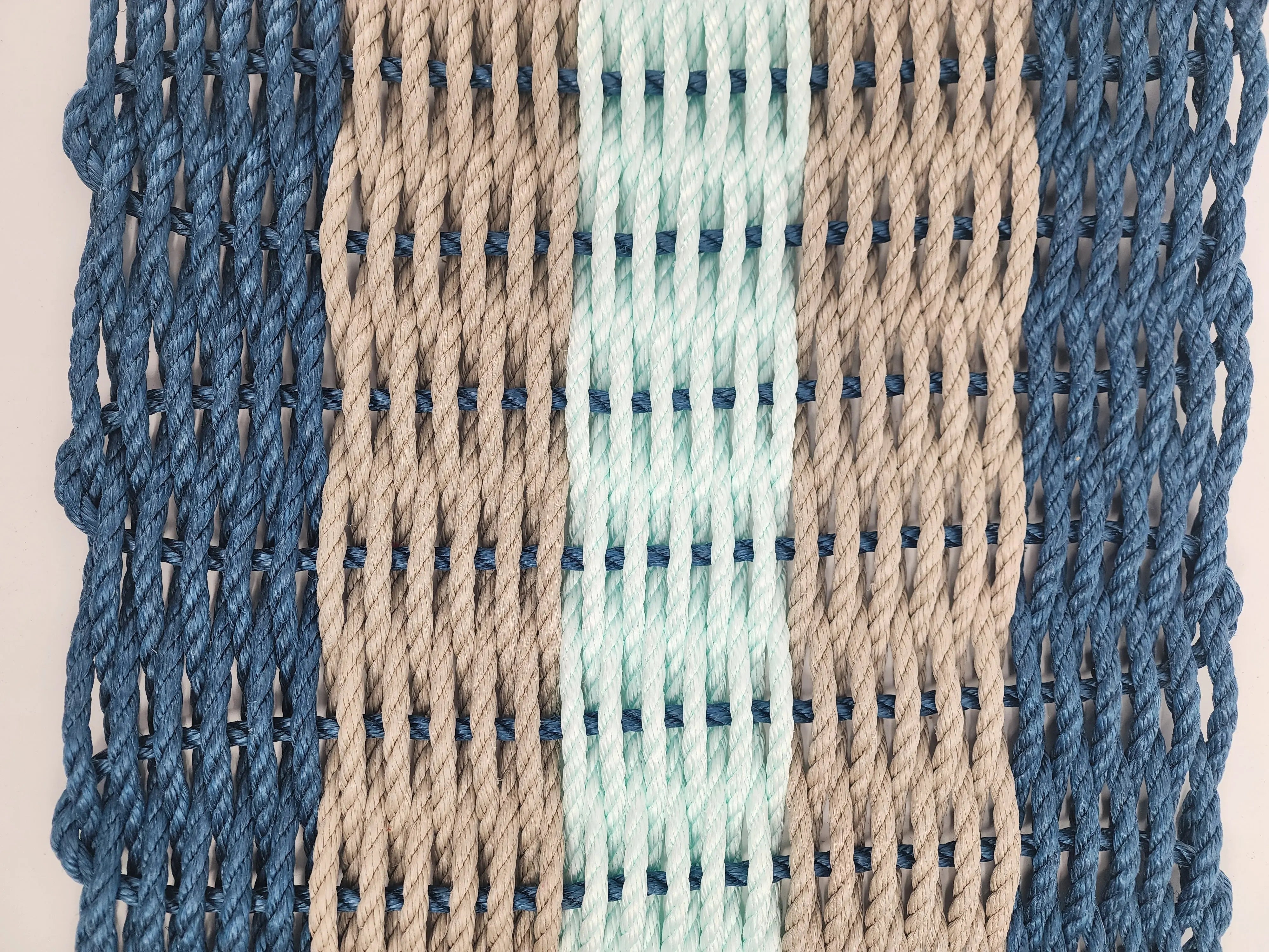 Five Stripe Rope Mat in navy, tan, and seafoam colors made from lobster rope