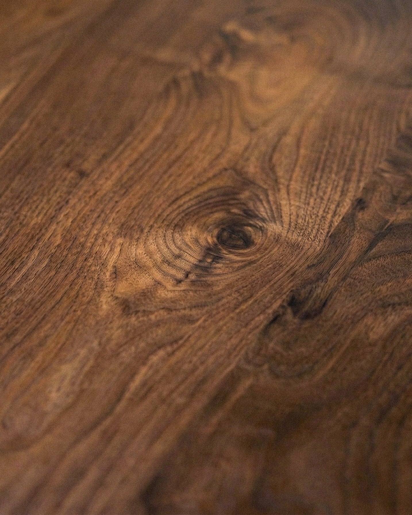 Modern round walnut dining table with sculptural pedestal base in a minimalist room