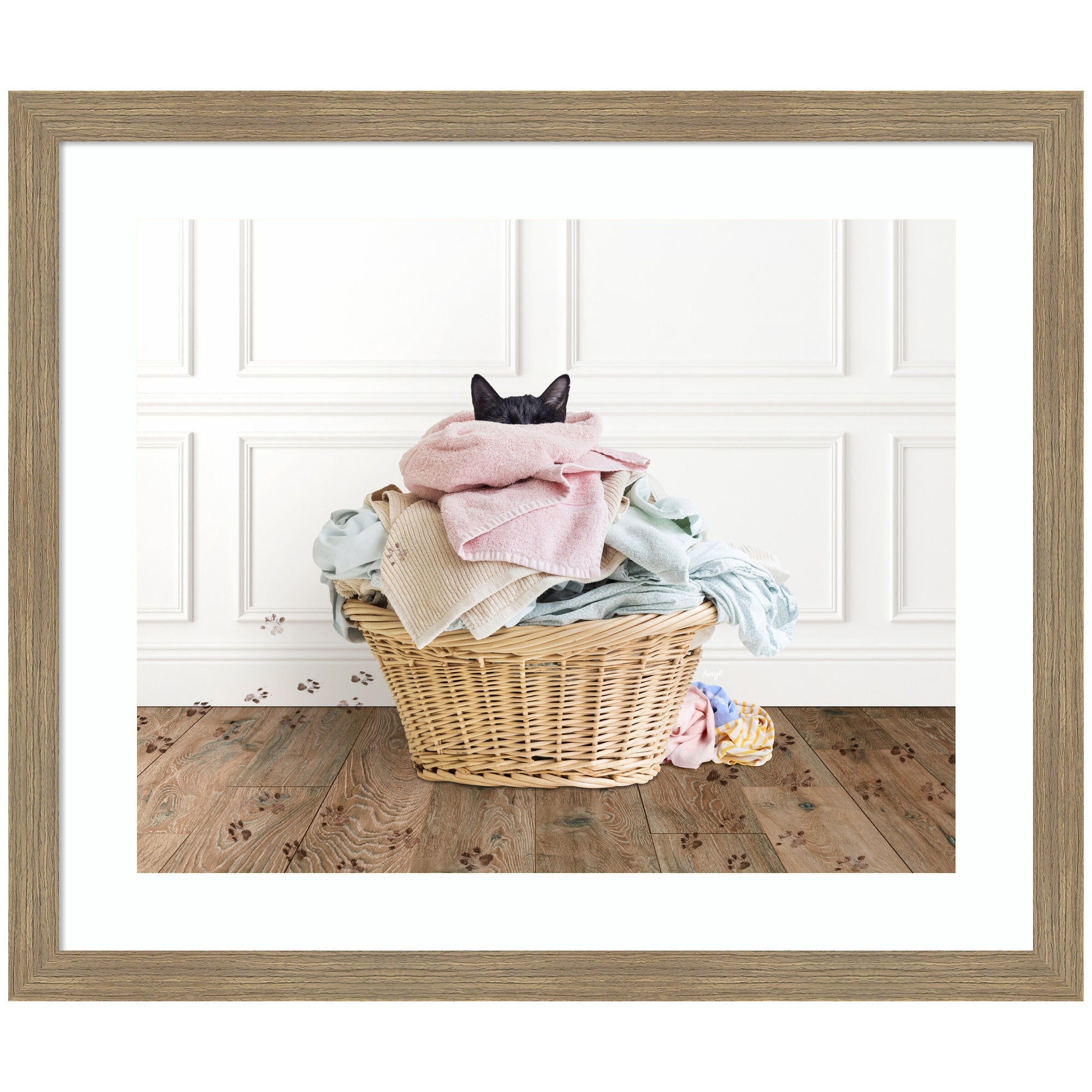 Framed art print of a black cat in a basket with pastel towels on a wooden floor by Amy Peterson