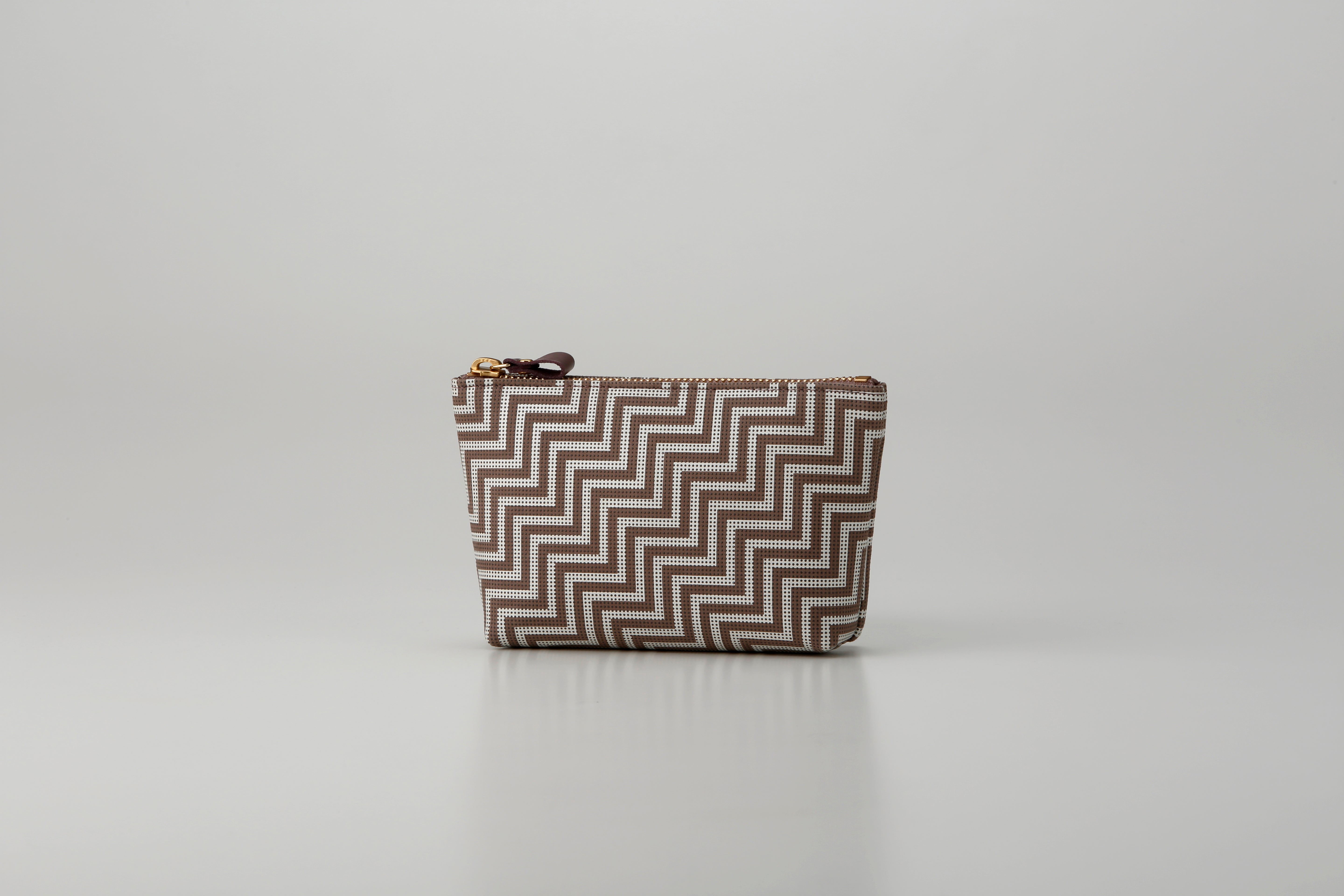 Rounded trapezoid brown deer skin pouch with white hand-drawn pattern and gray lacquered dots
