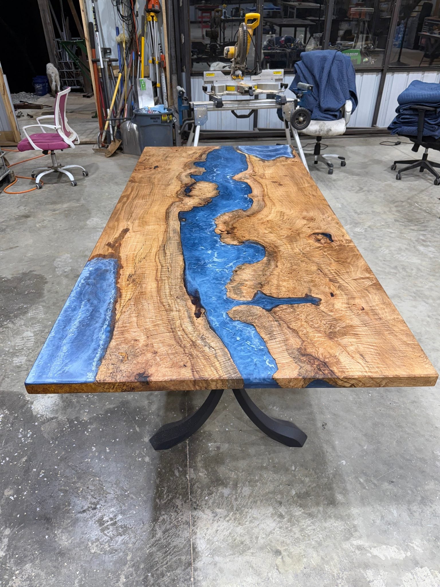 Maple Burl Epoxy River Dining Table with black steel base in a bright dining room