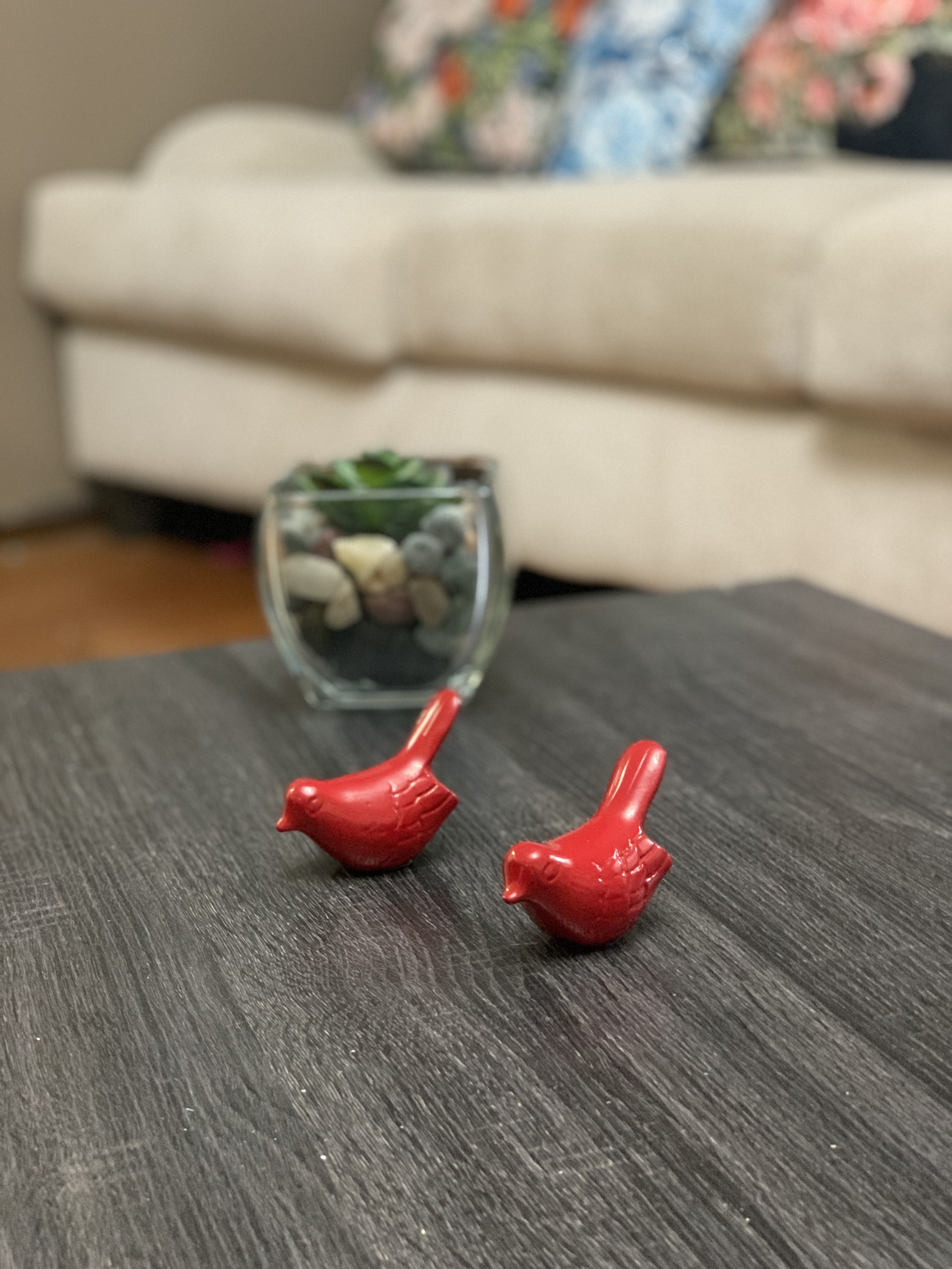 Set of two small glossy red bird figurines from Vibhsa placed on a neutral surface