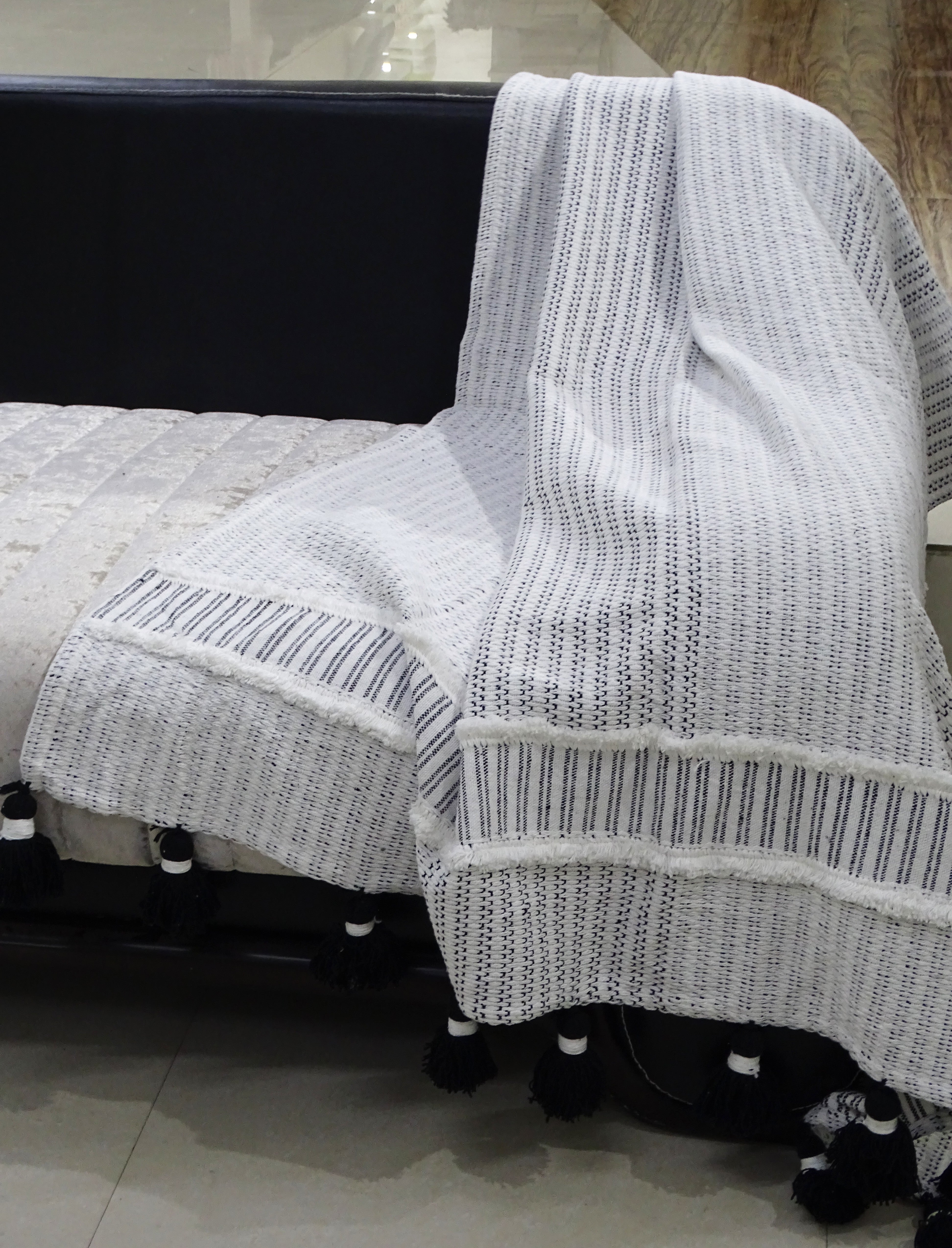 Hand loom Woven Textured Throw with Off White and Black Stripes and Black Tassels draped on a chair