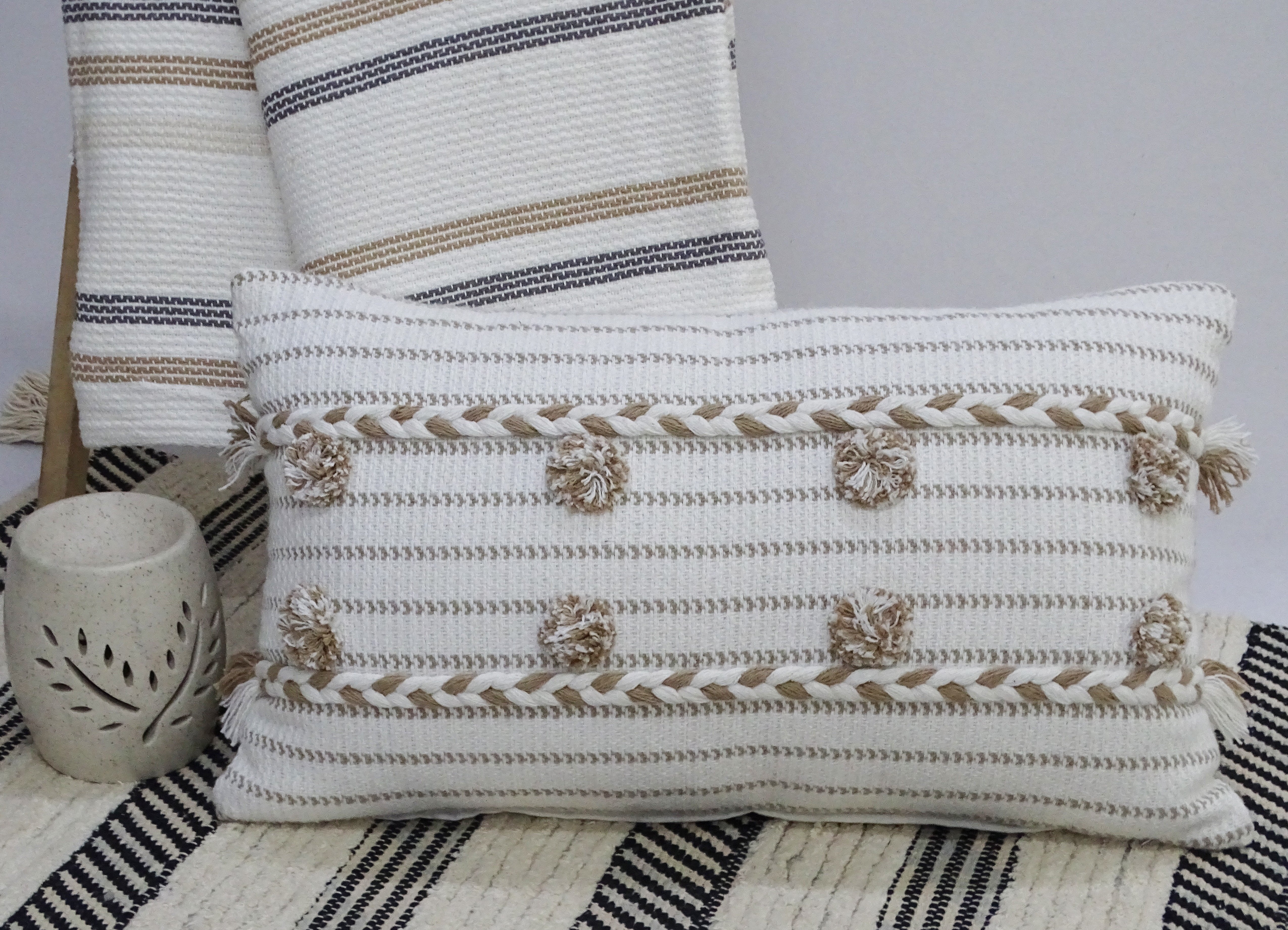 Handwoven 14" x 24" throw pillow in bright colors with braided textures and pom-poms on the edges