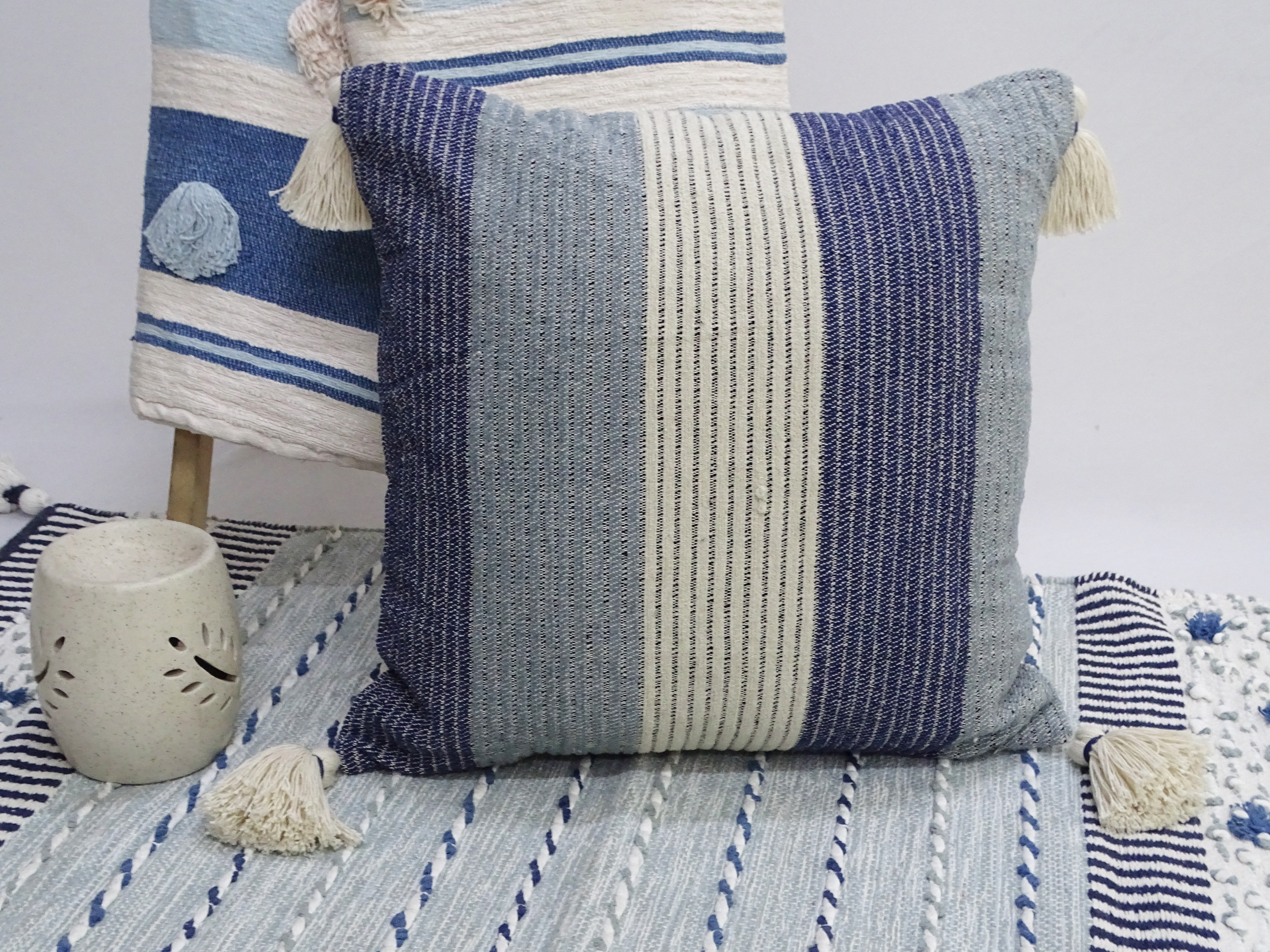 Colorful handwoven decorative throw pillow with tassels on a neutral sofa
