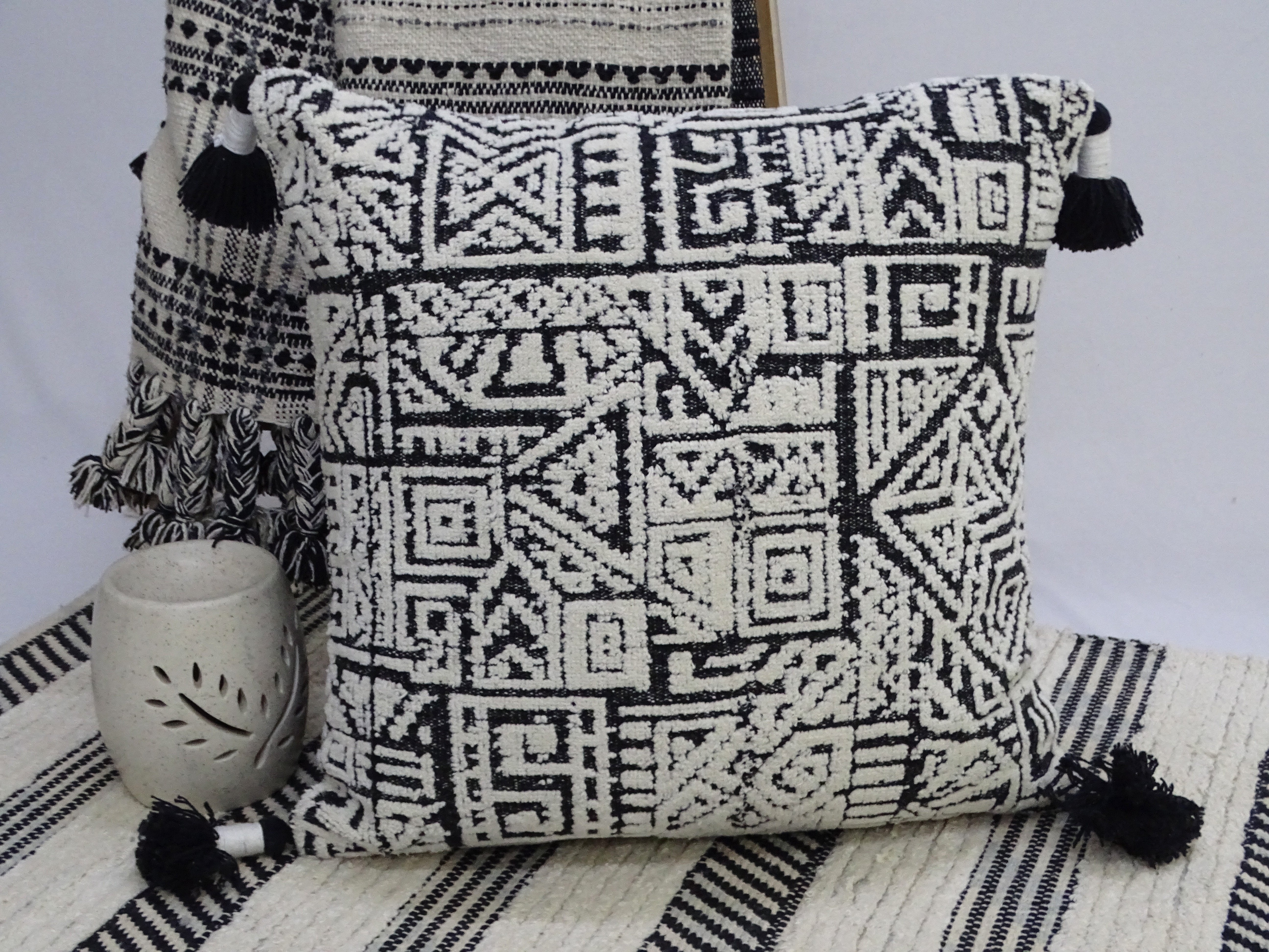 Colorful 20 by 20 inch throw pillow with corner tassels on a neutral surface