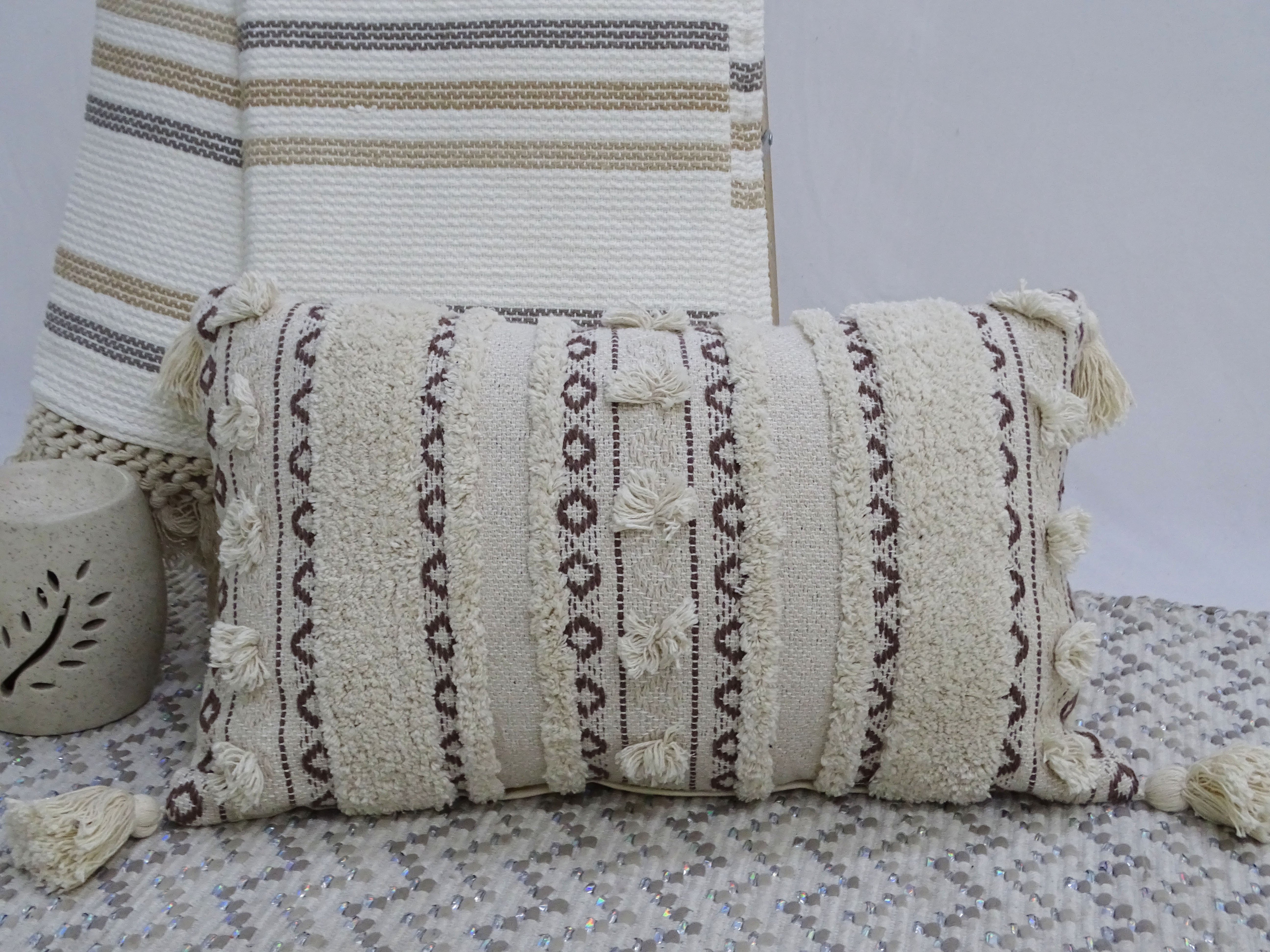Handwoven rectangular throw pillow with fringed corners on a neutral couch