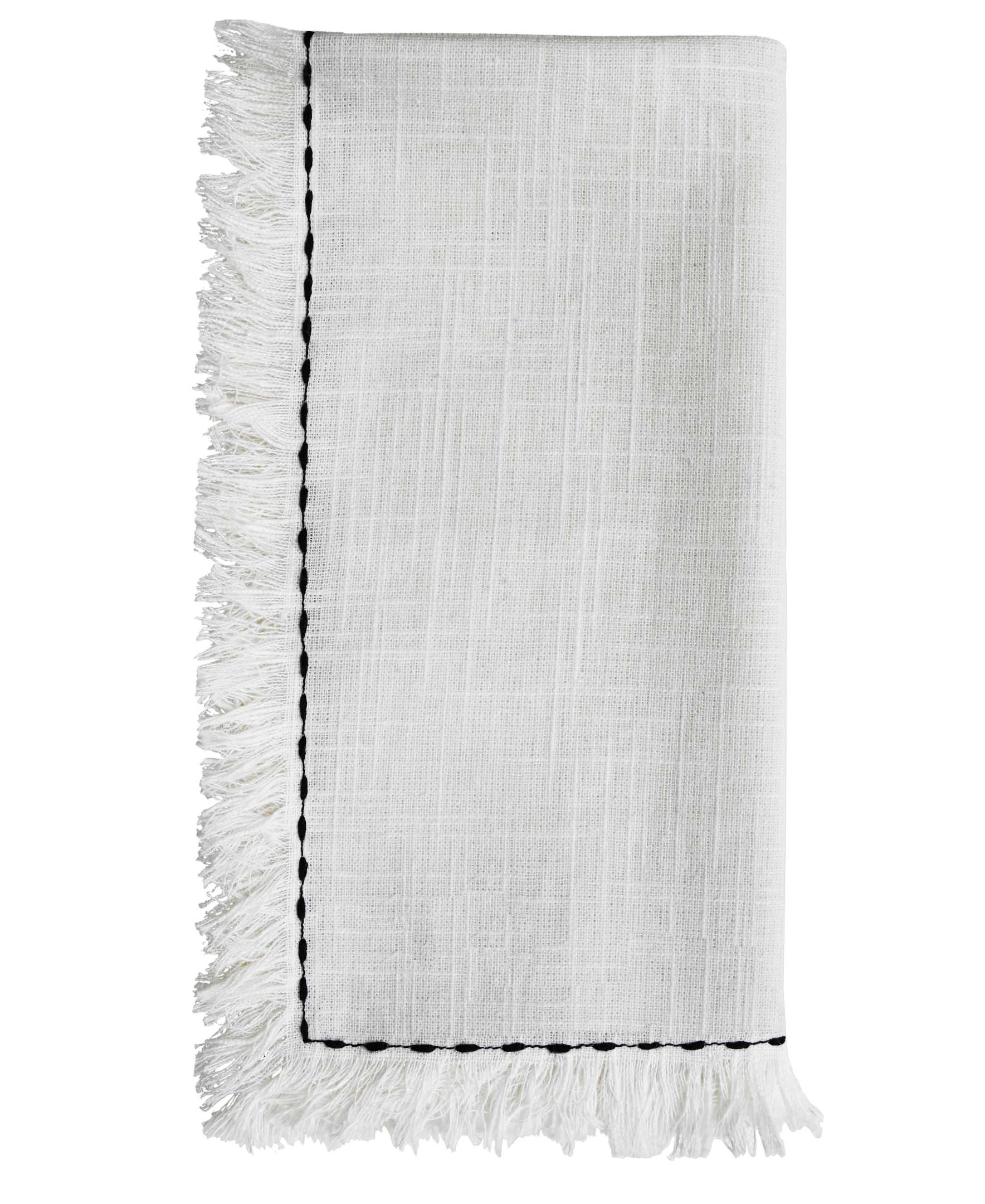 Set of four white cotton napkins with black embroidery placed on a wooden table as dining decor