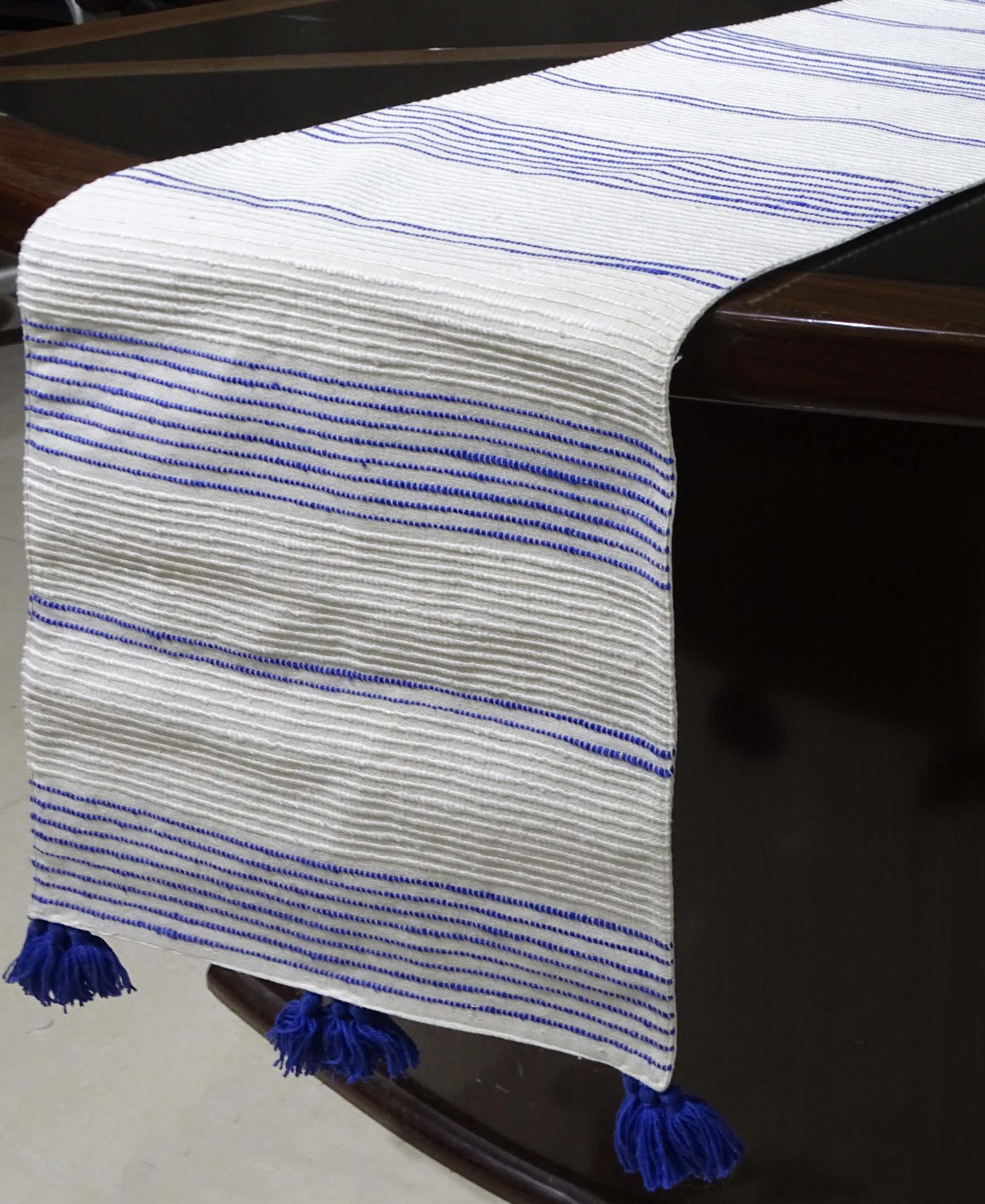 Cotton table runner laid across a dining table with subtle yellow and white stripes