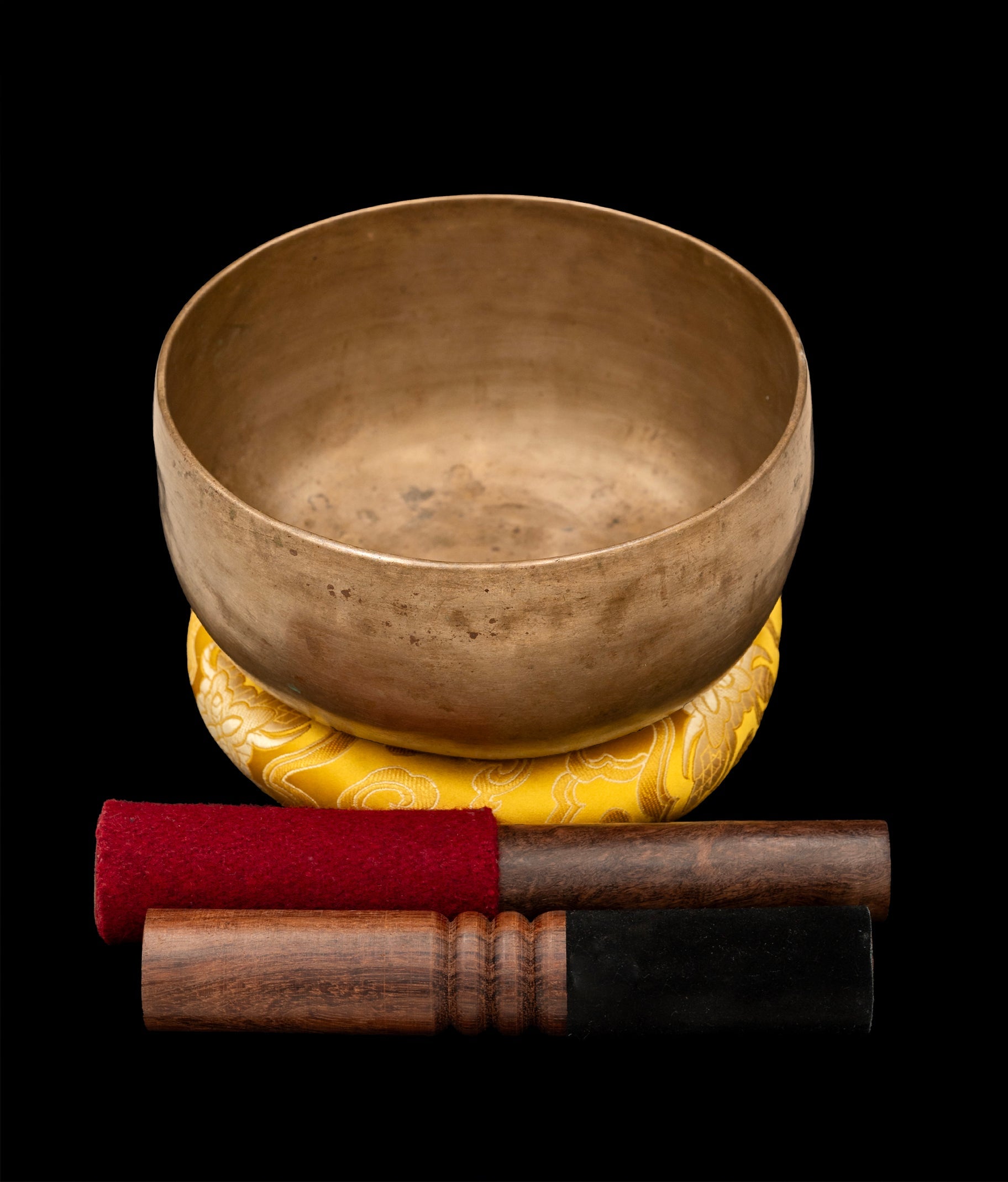 Antique Thadobati Singing Bowl with silk ring and two mallets on a wooden surface