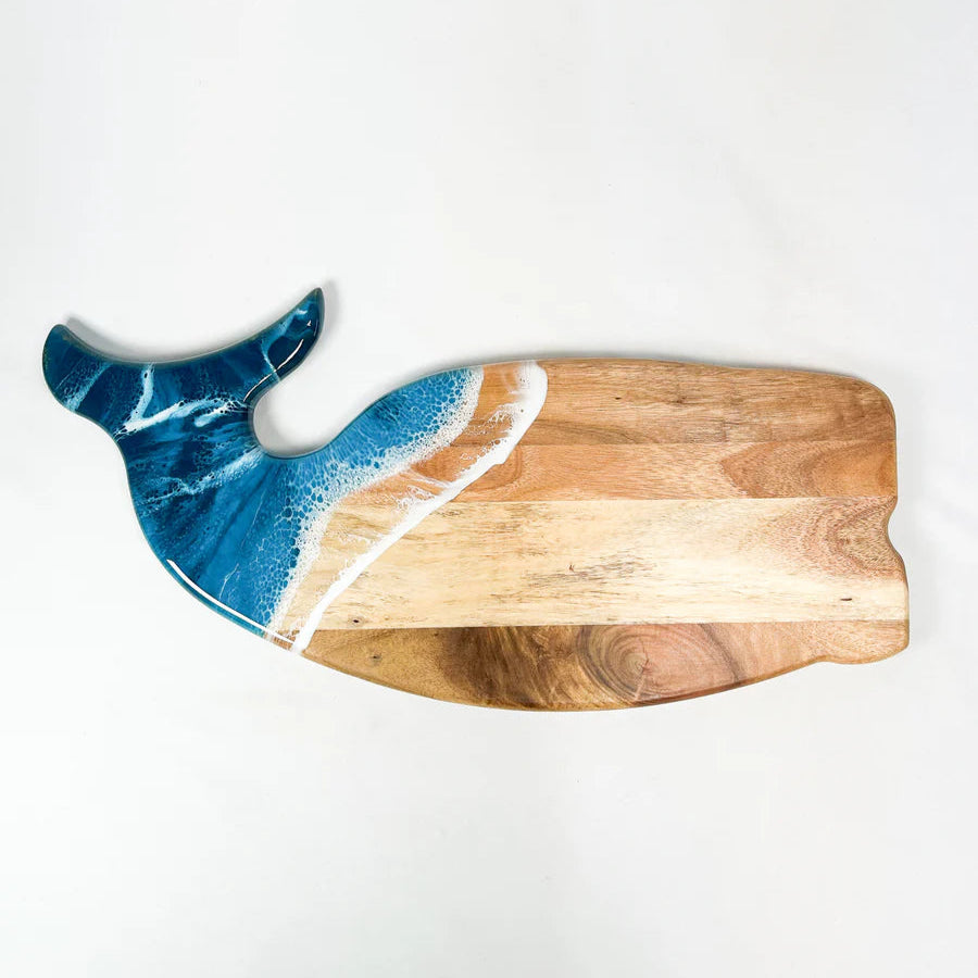 Wooden charcuterie board shaped like a whale with blue resin design on a white background