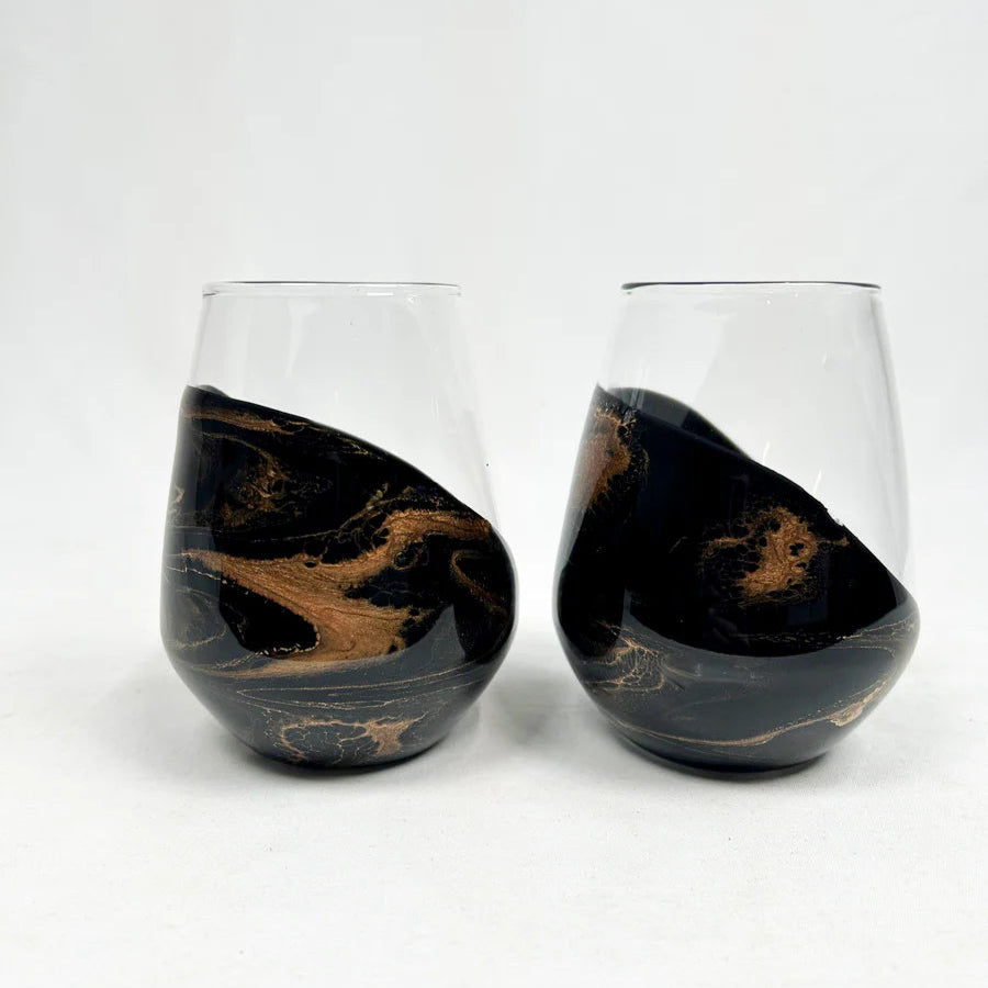 Two black and gold marbled stemless resin wine glasses on a white background