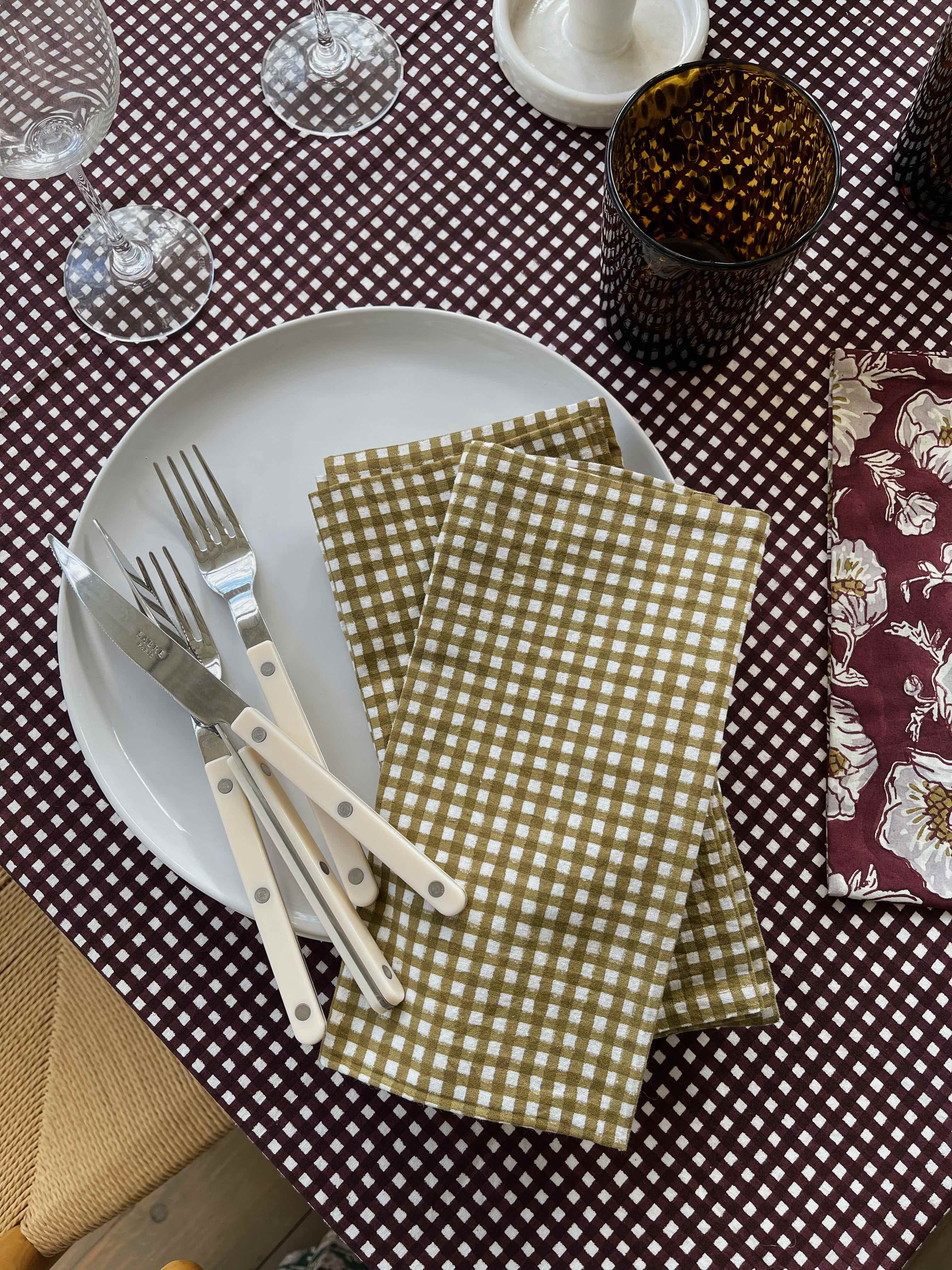 Set of six chartreuse and mustard gingham napkins stacked with a textured background