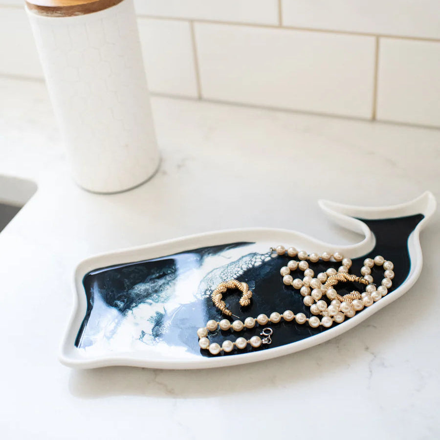 Jewelry on a resin decorative plate on a kitchen counter with a tiled wall background