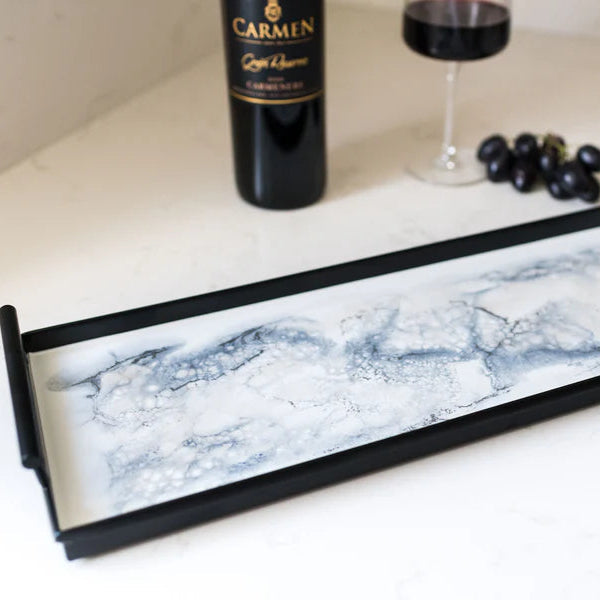Marble-patterned resin tray on a table with a bottle and grapes in the background