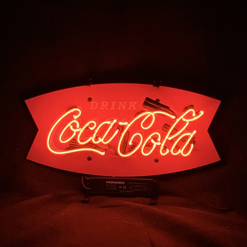 Drink Coca Cola Real Neon Sign lit up against a wall