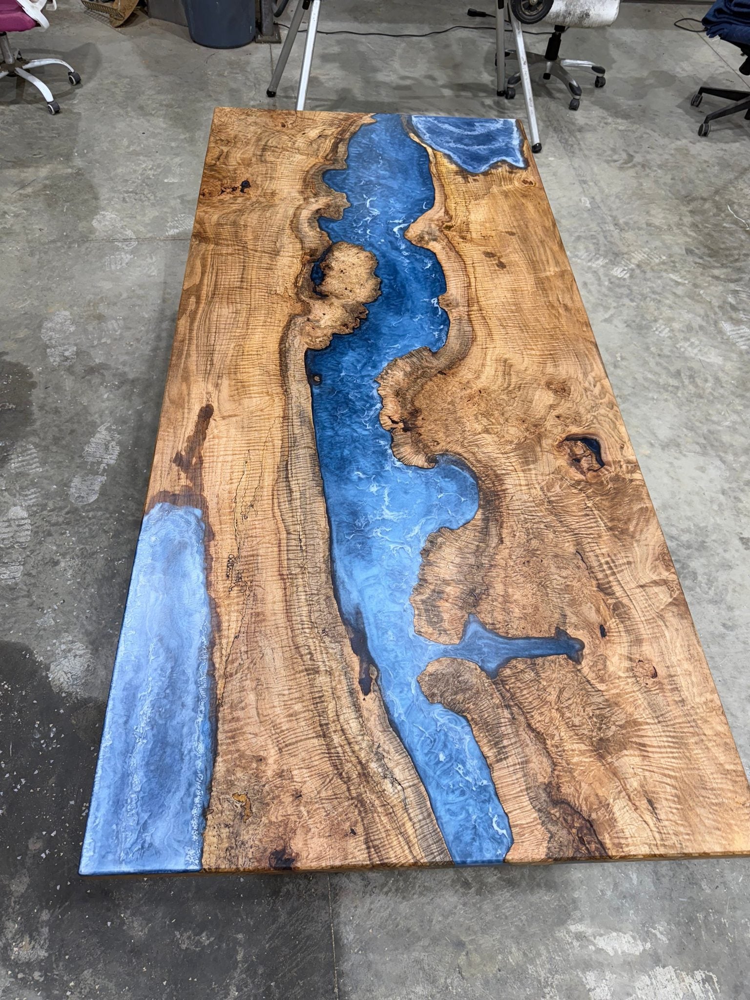 Maple Burl Epoxy River Dining Table with black steel base in a bright dining room