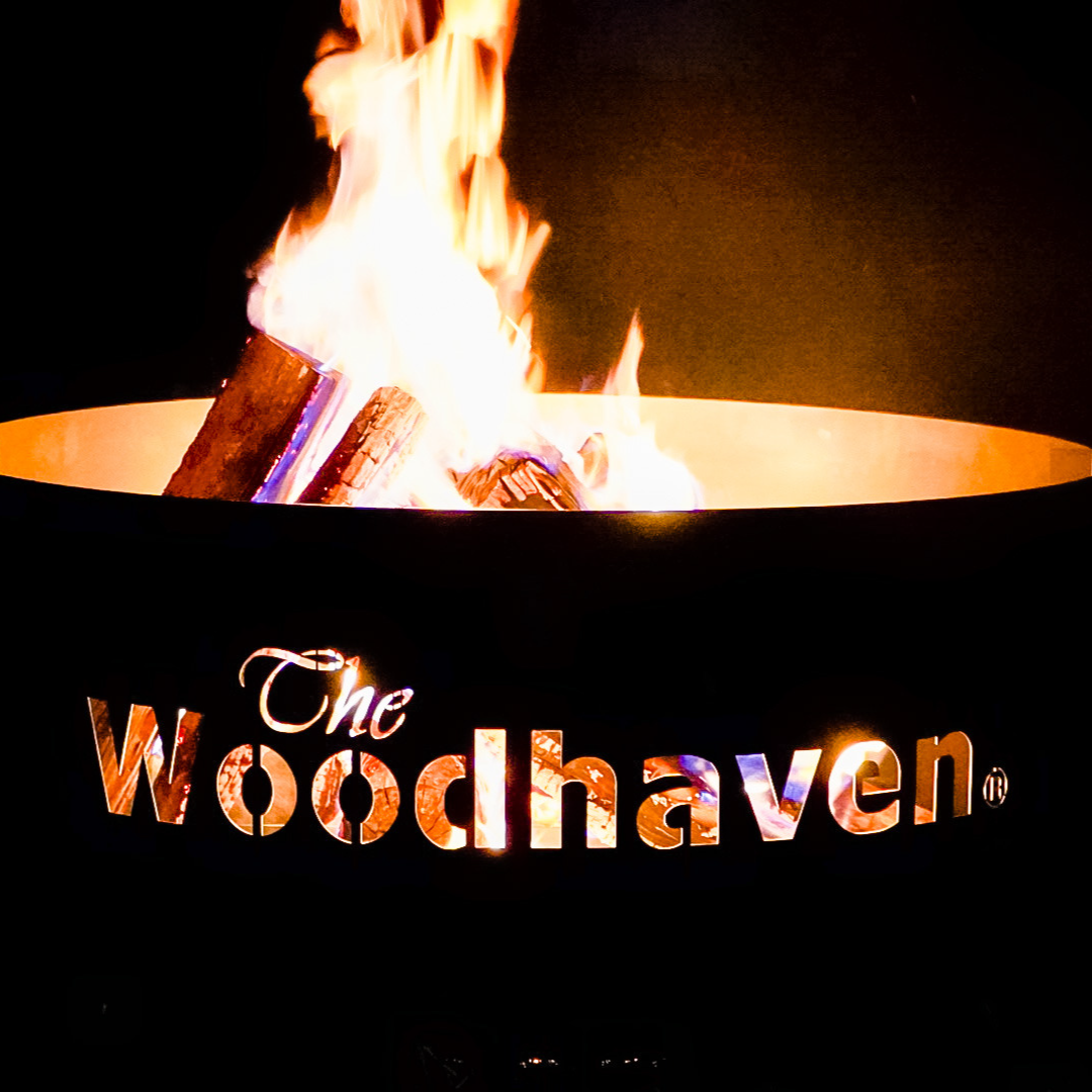 Woodhaven Portable Steel Fire Pit with stainless steel cooking grate, shown outdoors