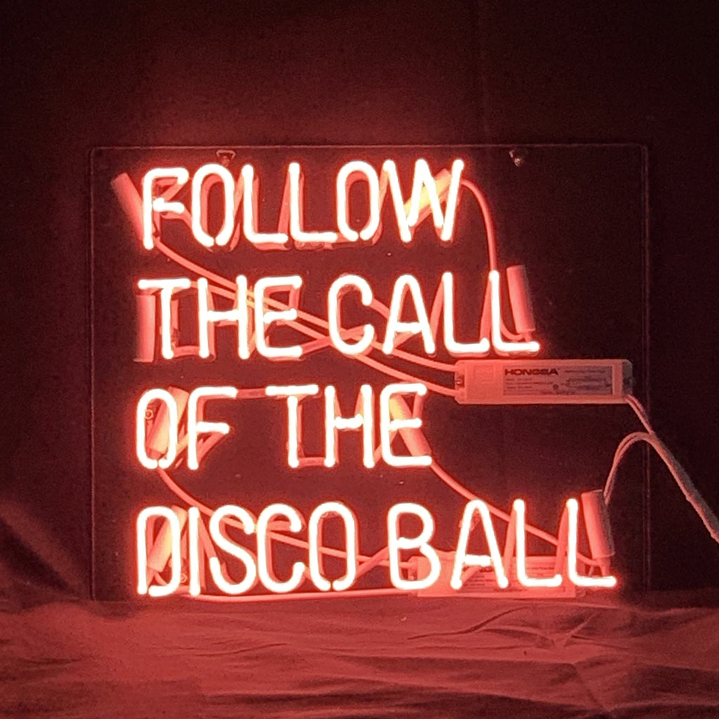 Follow The Call of The Disco Ball Neon Light Sign glowing with neon pink text on acrylic backing