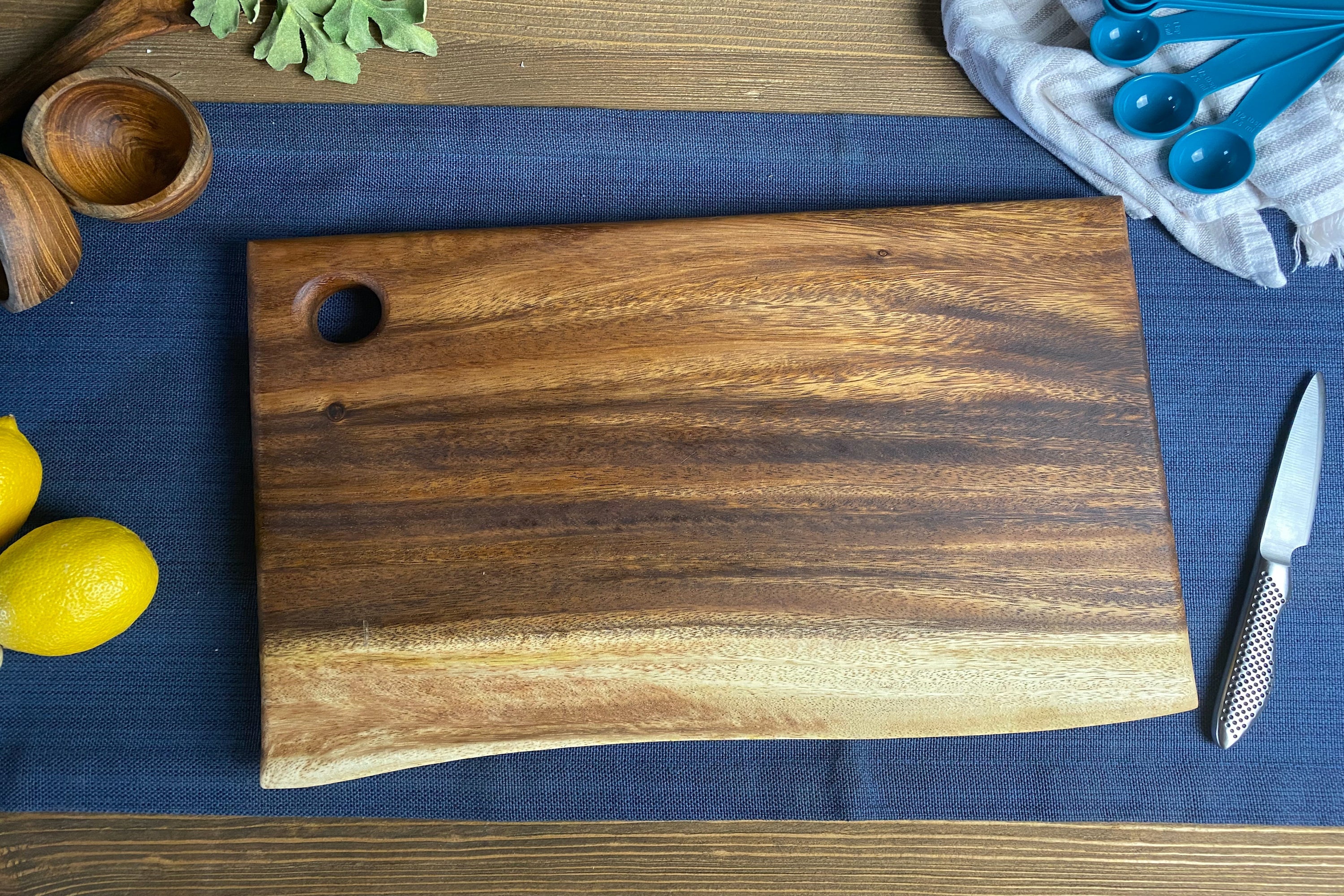 Medium live edge square end cutting board with hanging hole on a white background