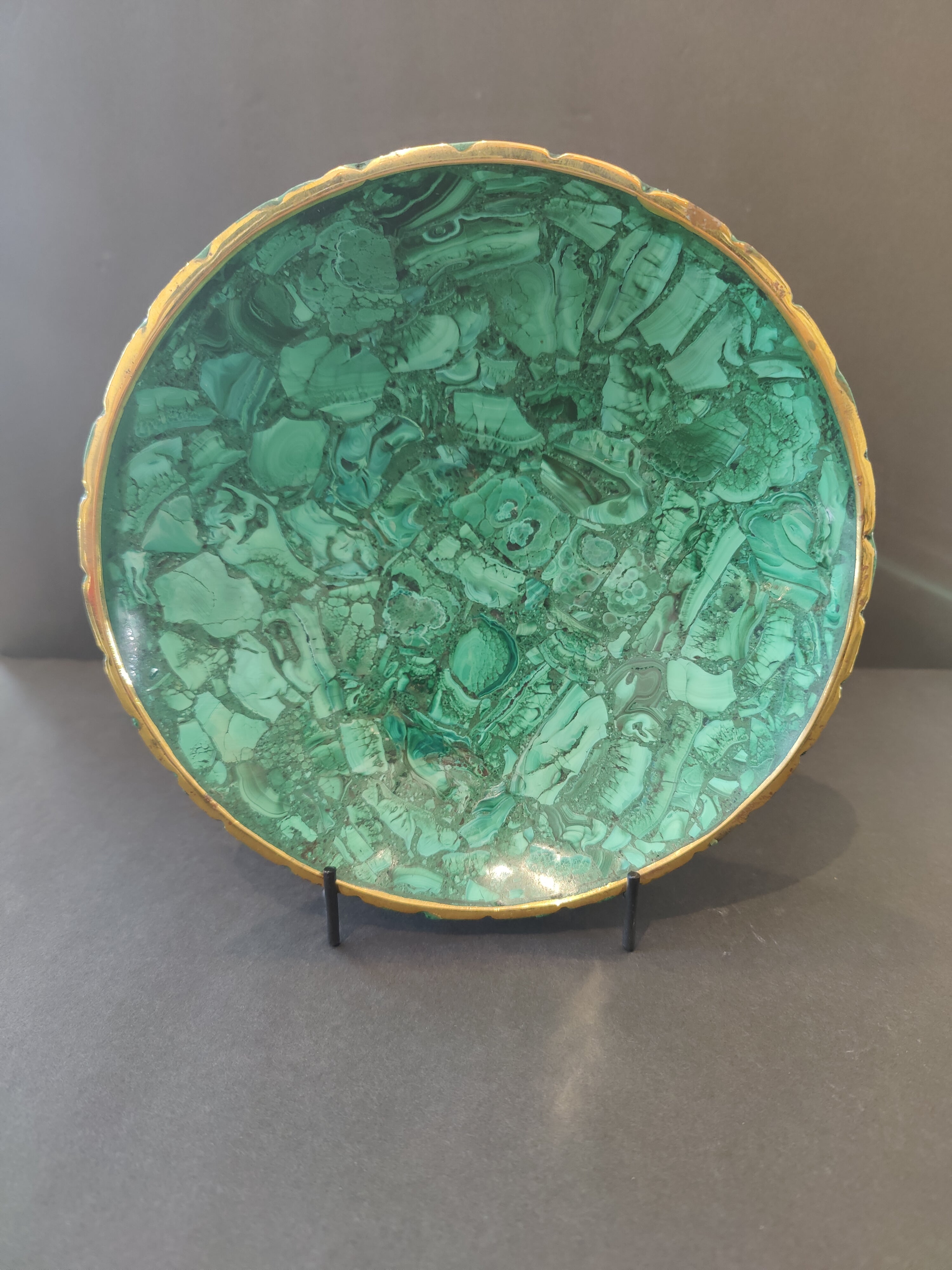 Malachite decorative bowl with gold rim shown on wooden surface
