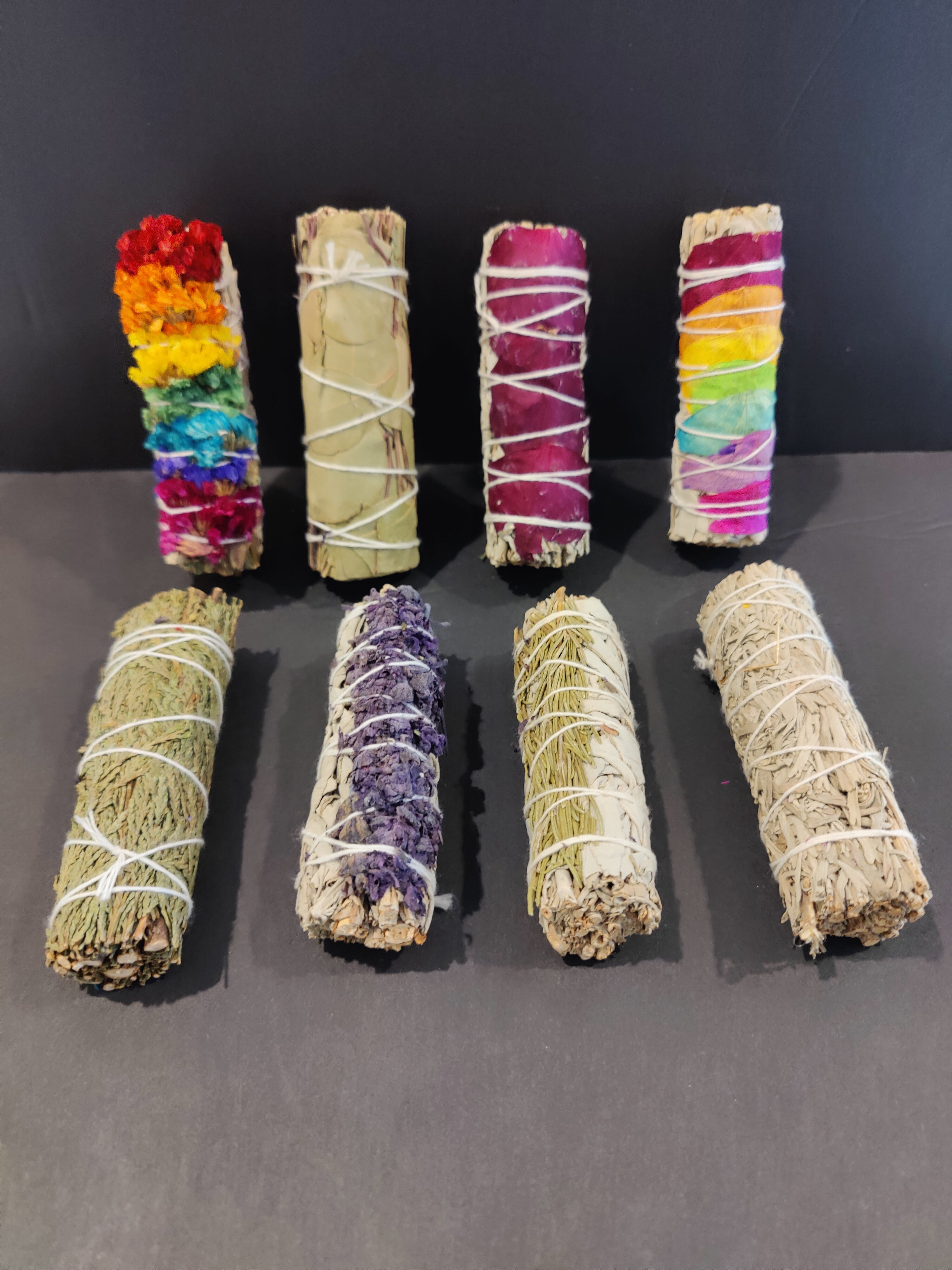 Assorted Sage Bundle Smudge Sticks with botanical elements laid out on surface