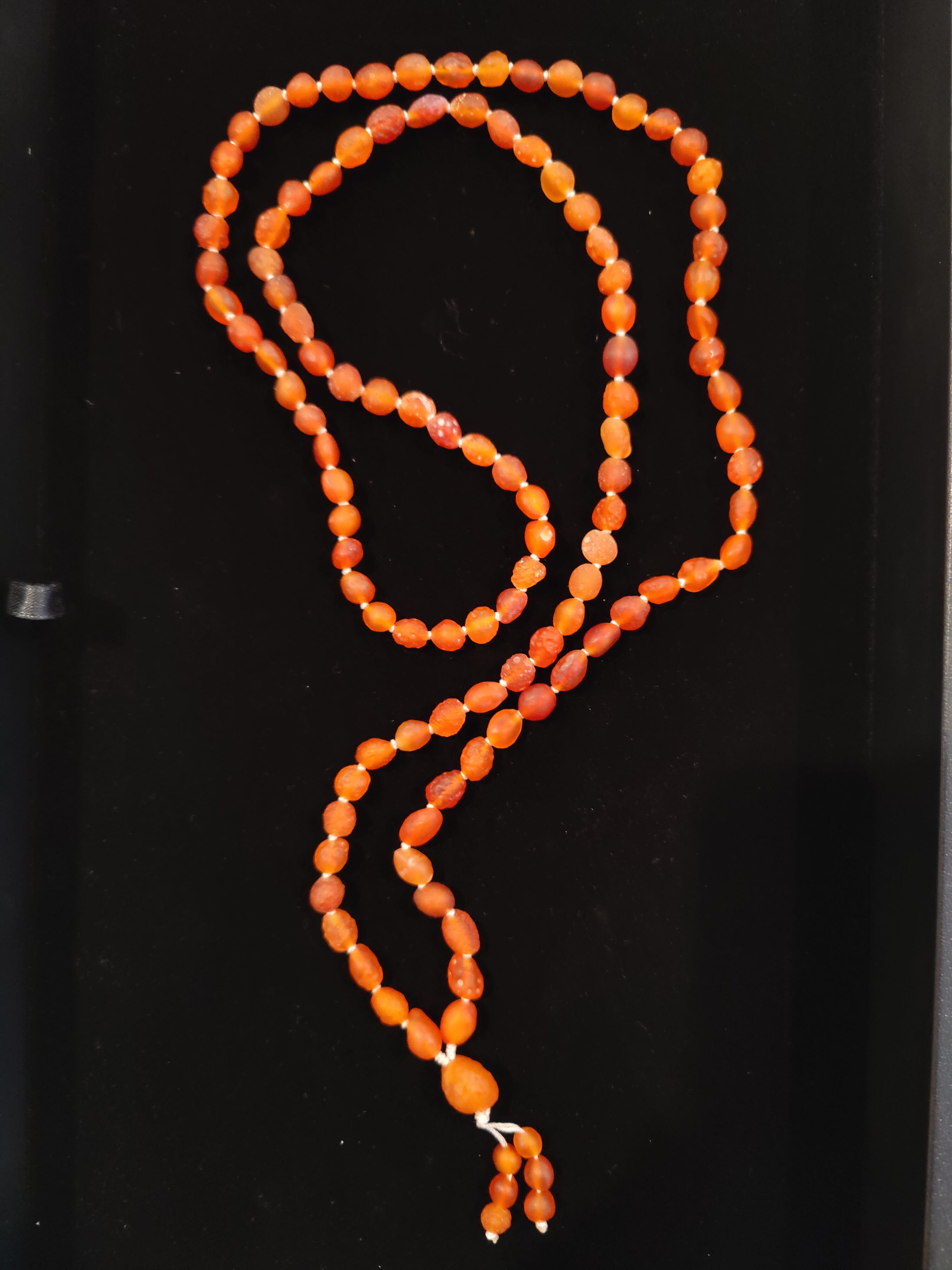 Close-up of Red Carnelian Gobi Desert Agate 108 bead mala necklace on a neutral background