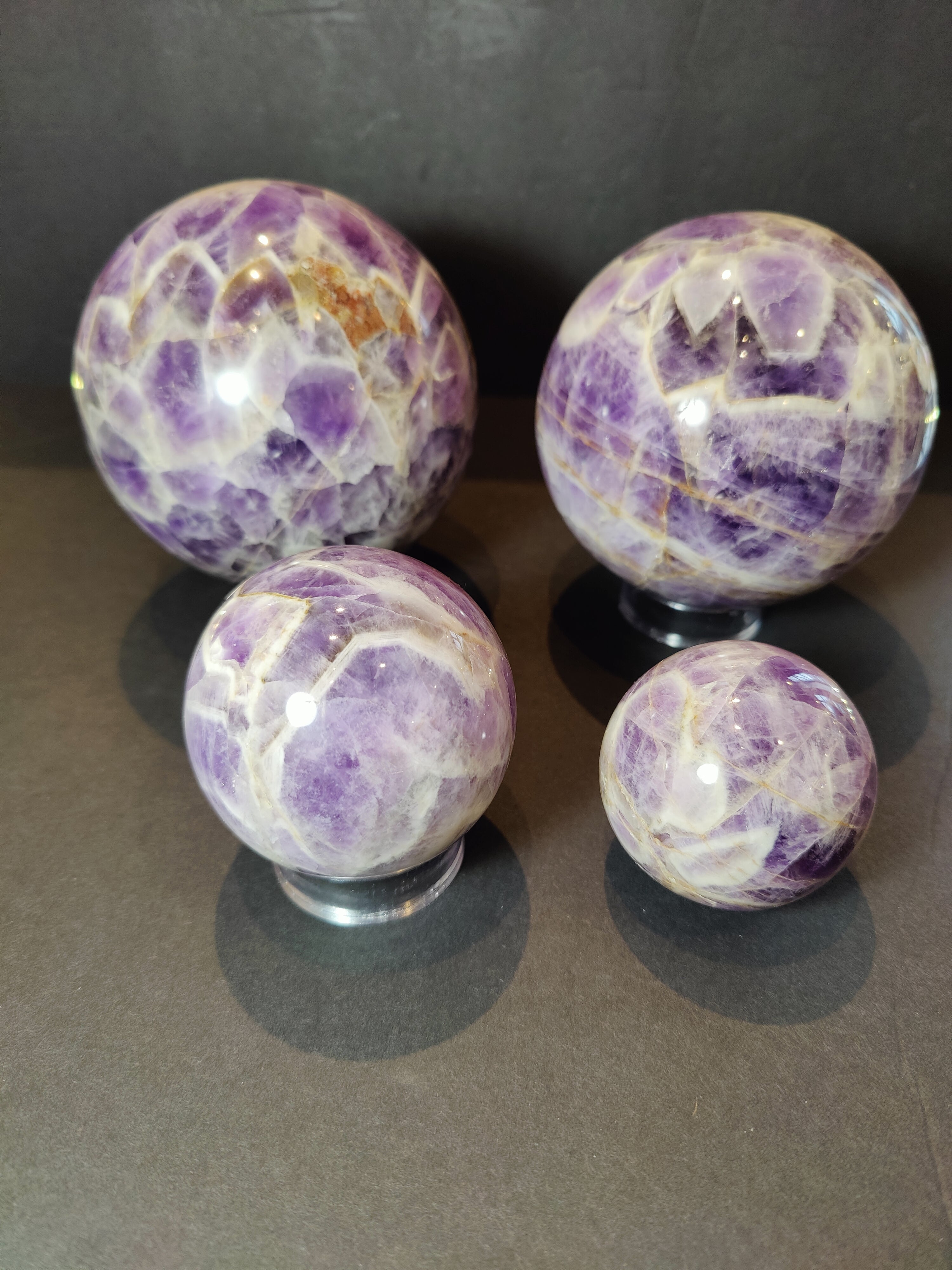 Chevron Amethyst polished purple sphere resting on a surface showing banded quartz patterns.