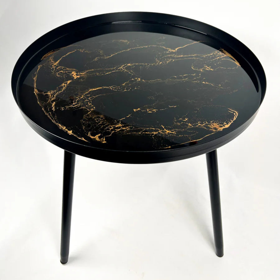 Round black small resin table with gold marble pattern on a white background
