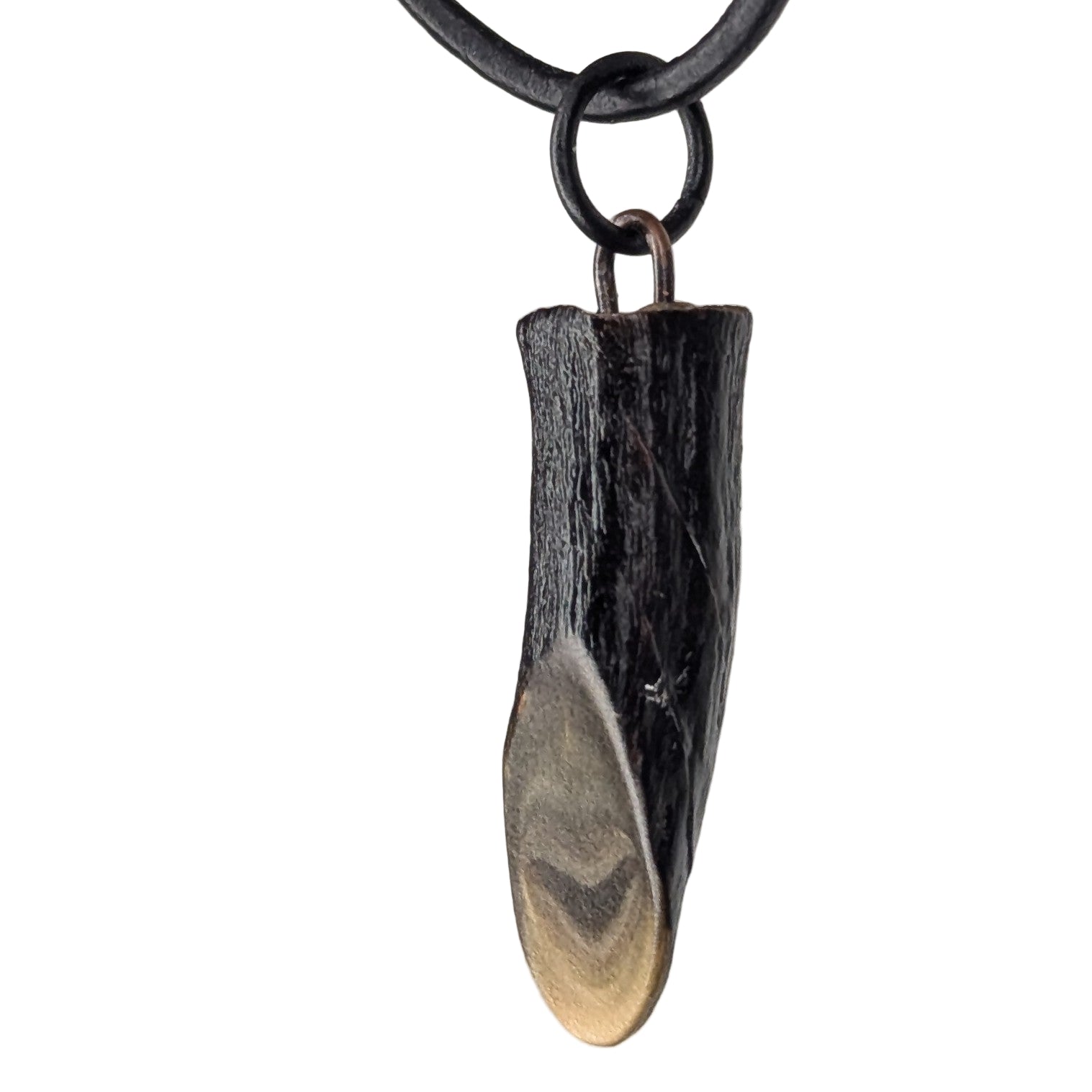 Turvex pendant necklace resting on a natural surface, showing its organic shape and warm surface textures.
