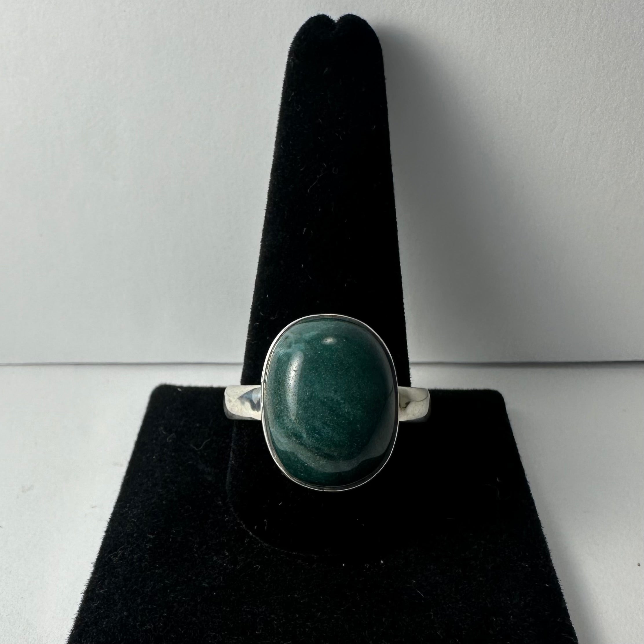 Green Serpentine ring with .925 Sterling Silver band, displayed on a rock