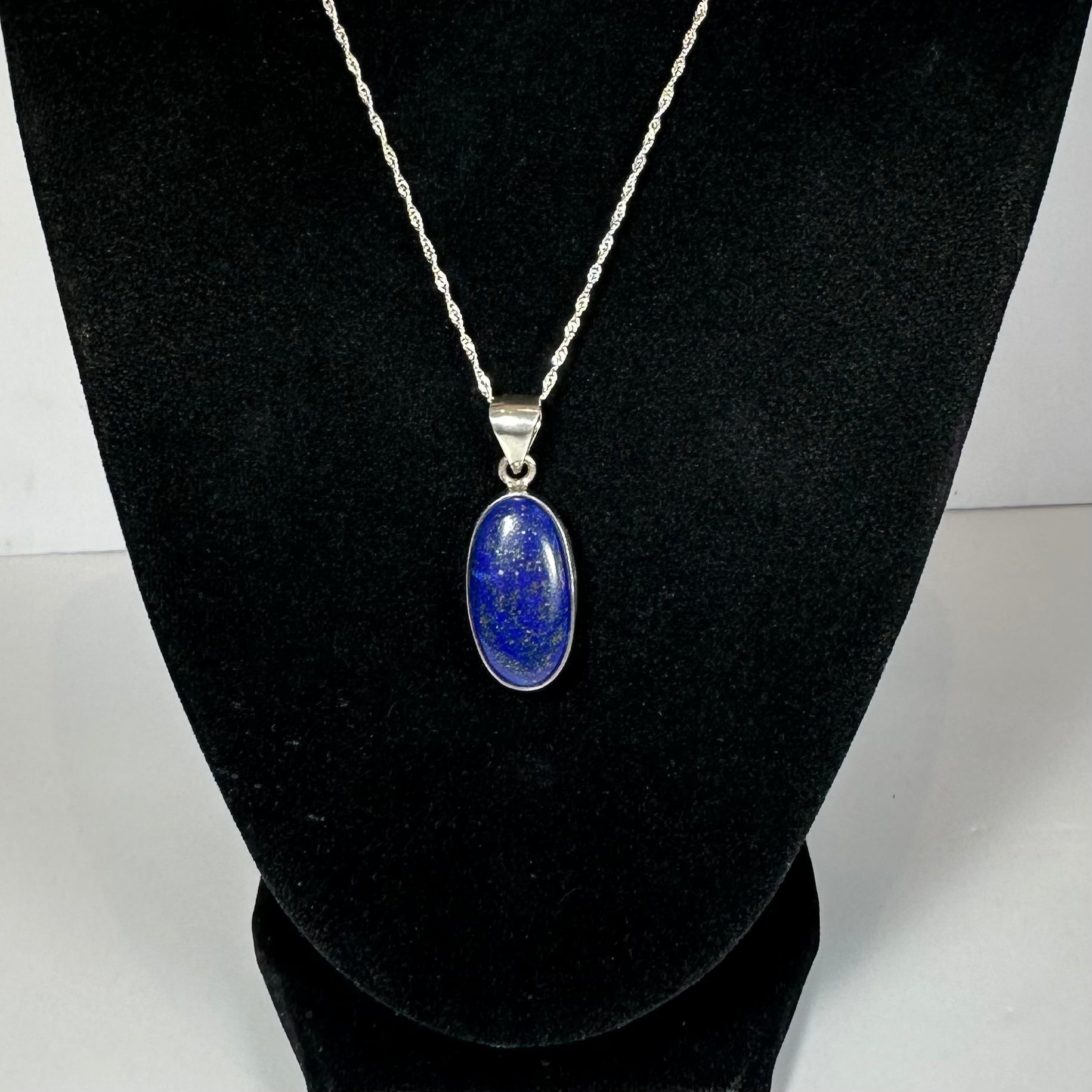 Close-up image of a Lapis Lazuli Pendant set in sterling silver on a neutral textured background