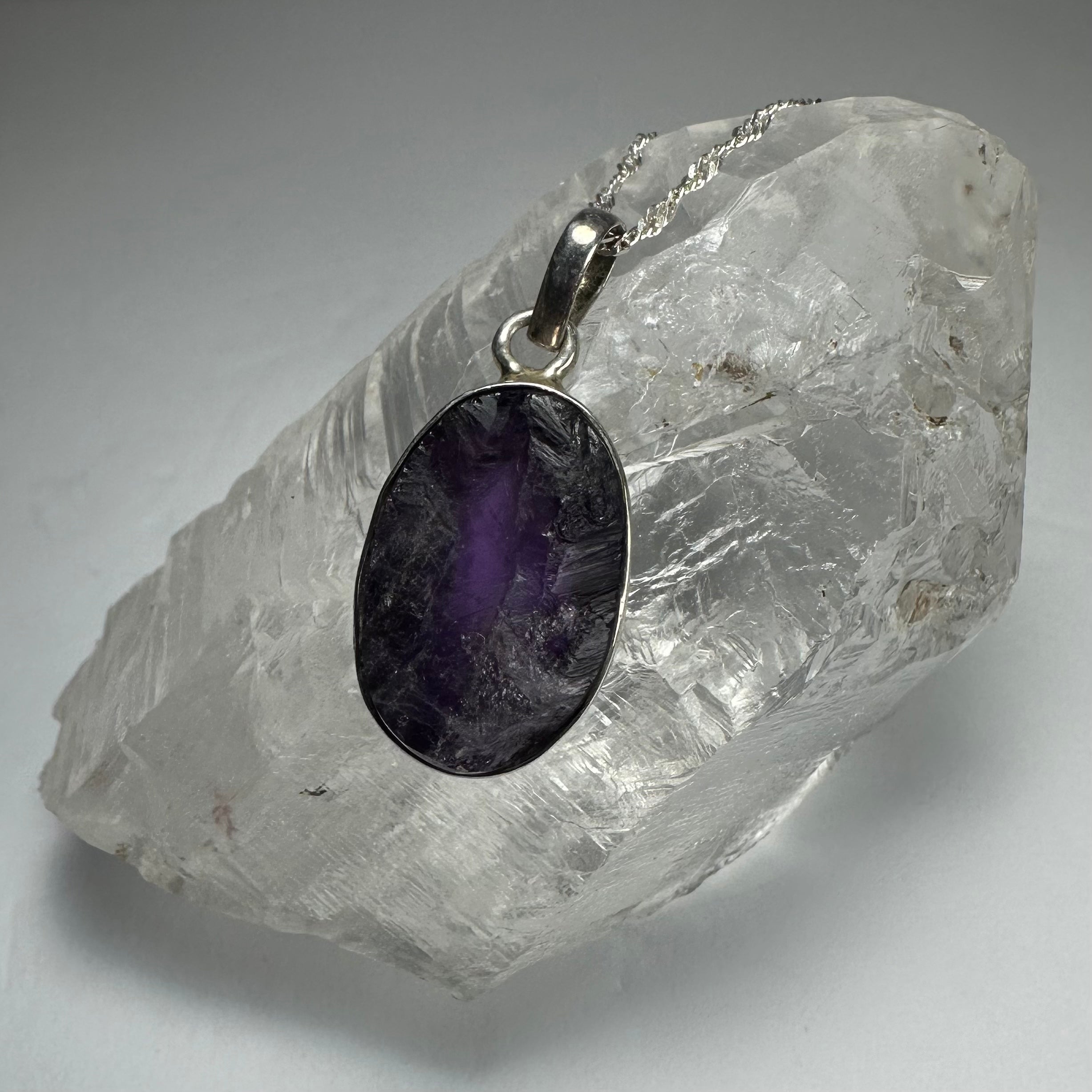 Close-up of Natural Rough Amethyst Pendant with rough purple stone attached to a sterling silver clasp