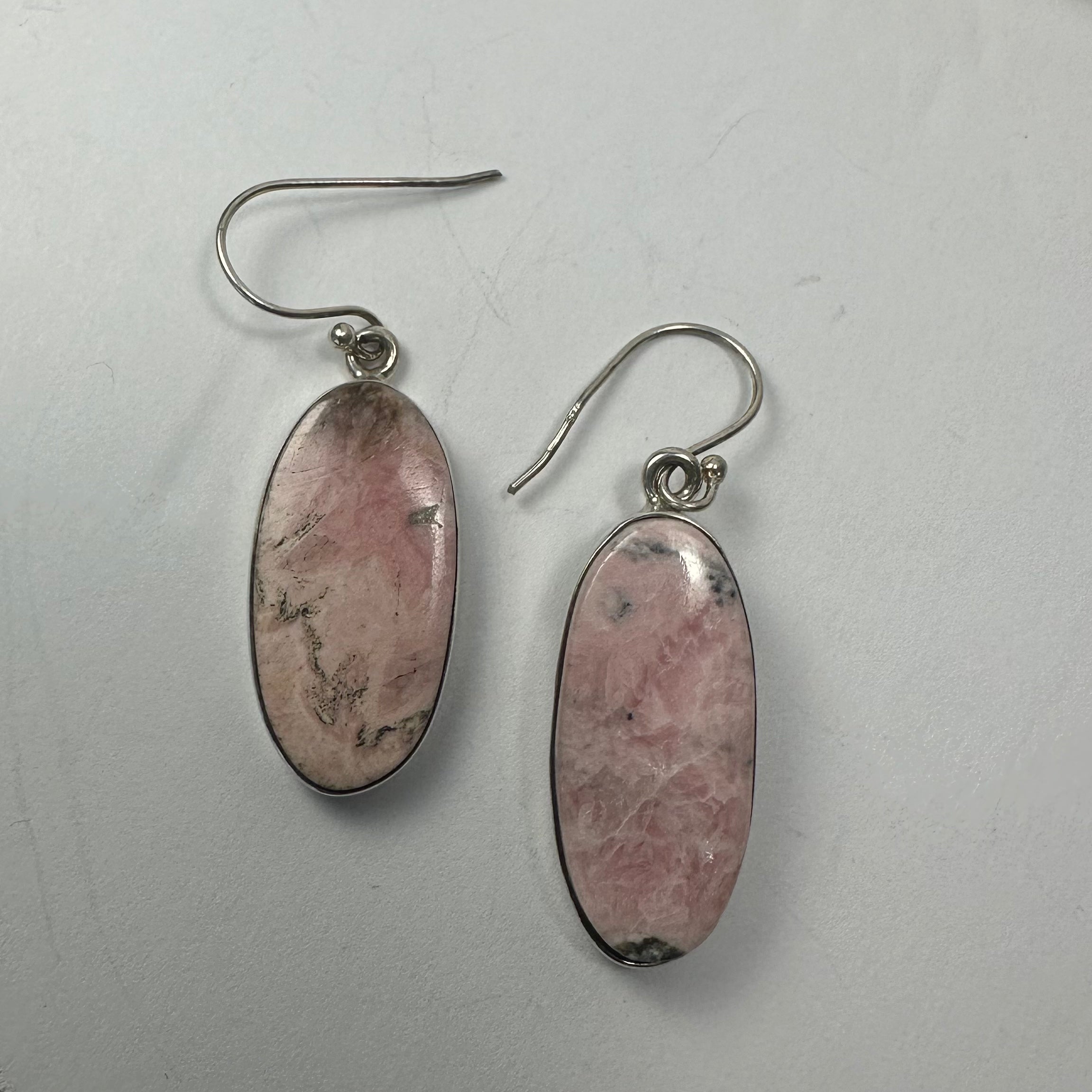 Close-up image of Rhodonite Earrings in diamond and oblong shapes with silver clasps