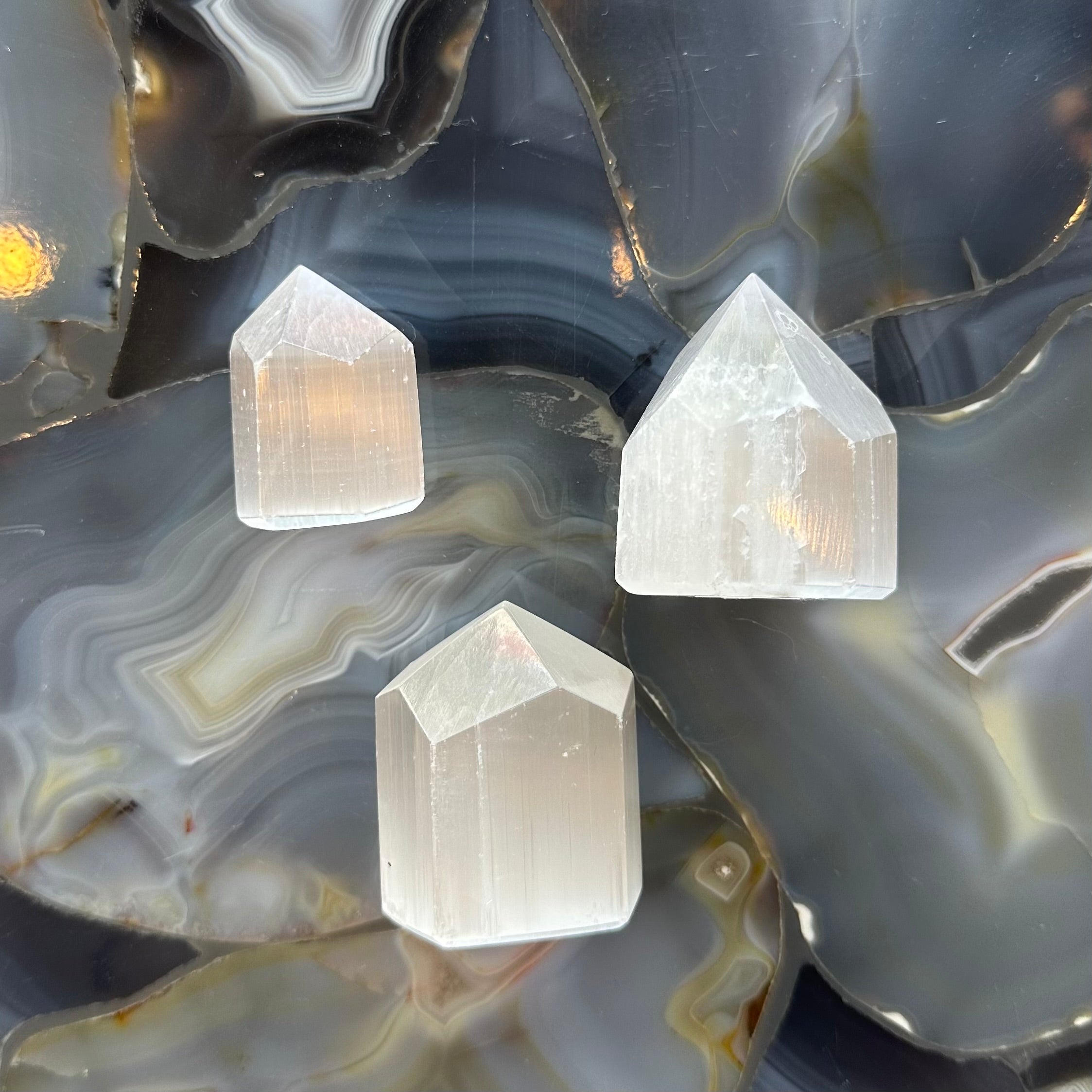 Small translucent Selenite Obelisk Tower with soft white and clear striations standing on a surface