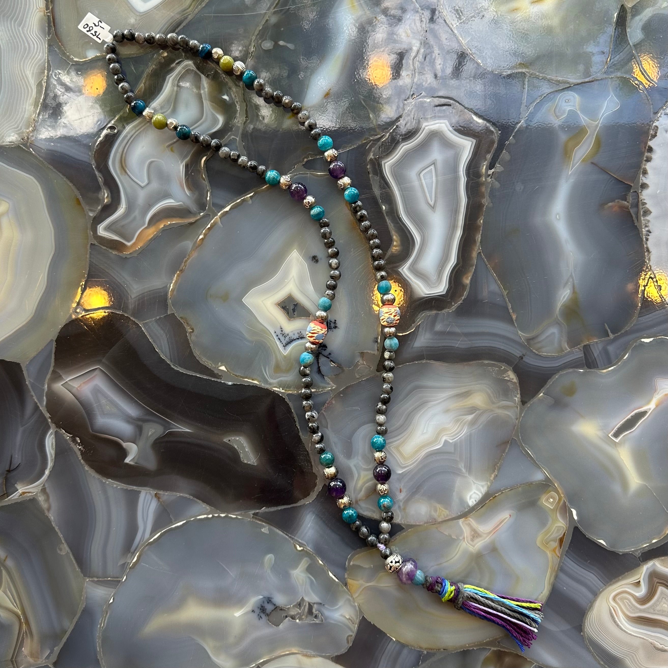 Close-up view of Larvikite Mala with mixed stone beads on a neutral surface