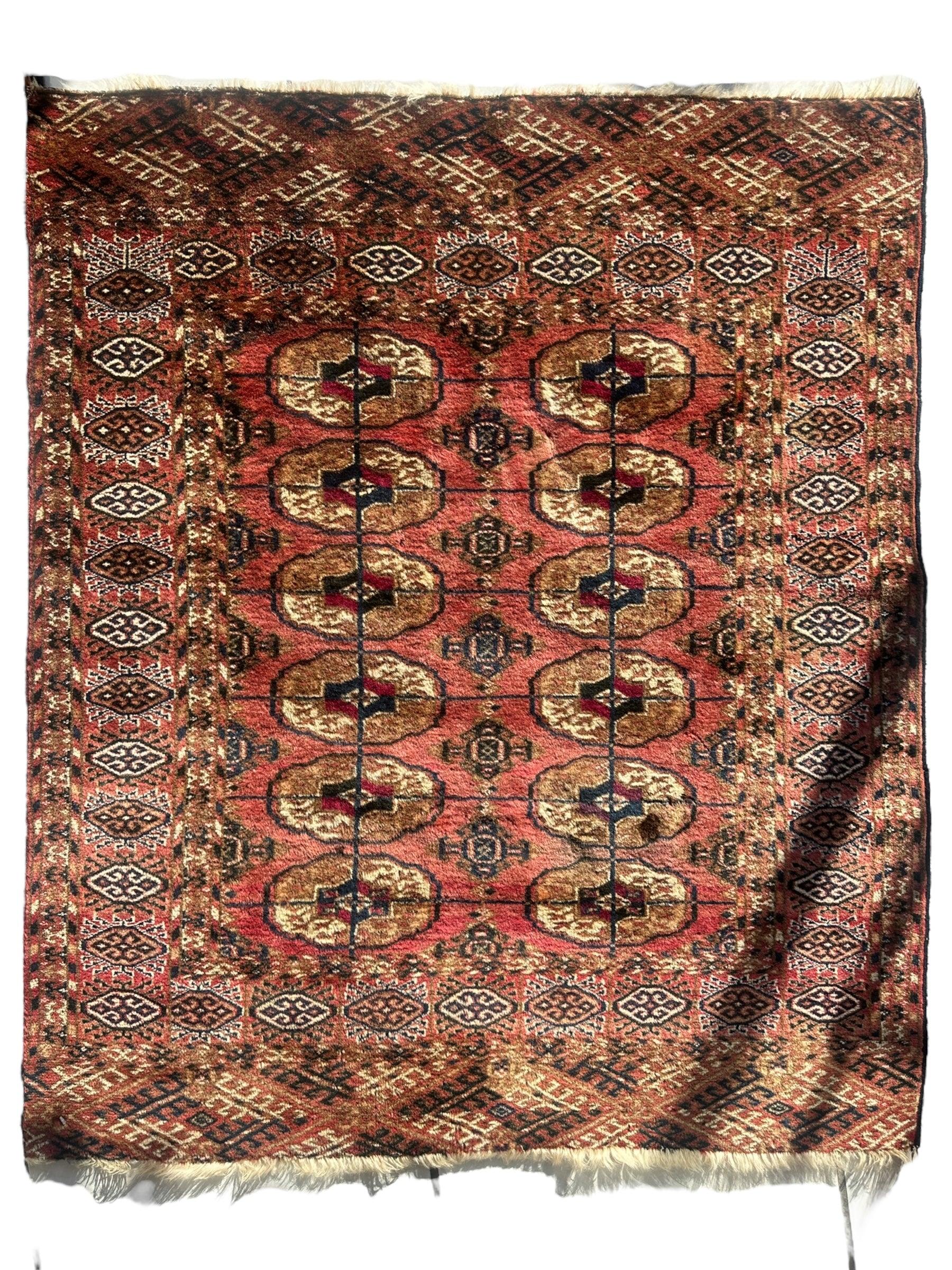 Vintage Tribal Turkoman Tekke Rug spread out displaying intricate tribal patterns in natural light