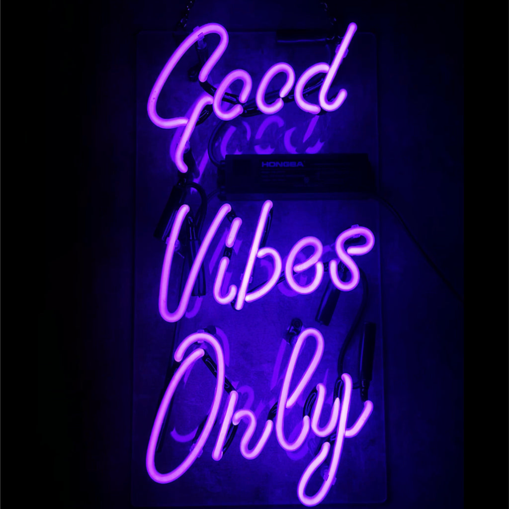 Purple glowing Good Vibes Only neon sign mounted on wall