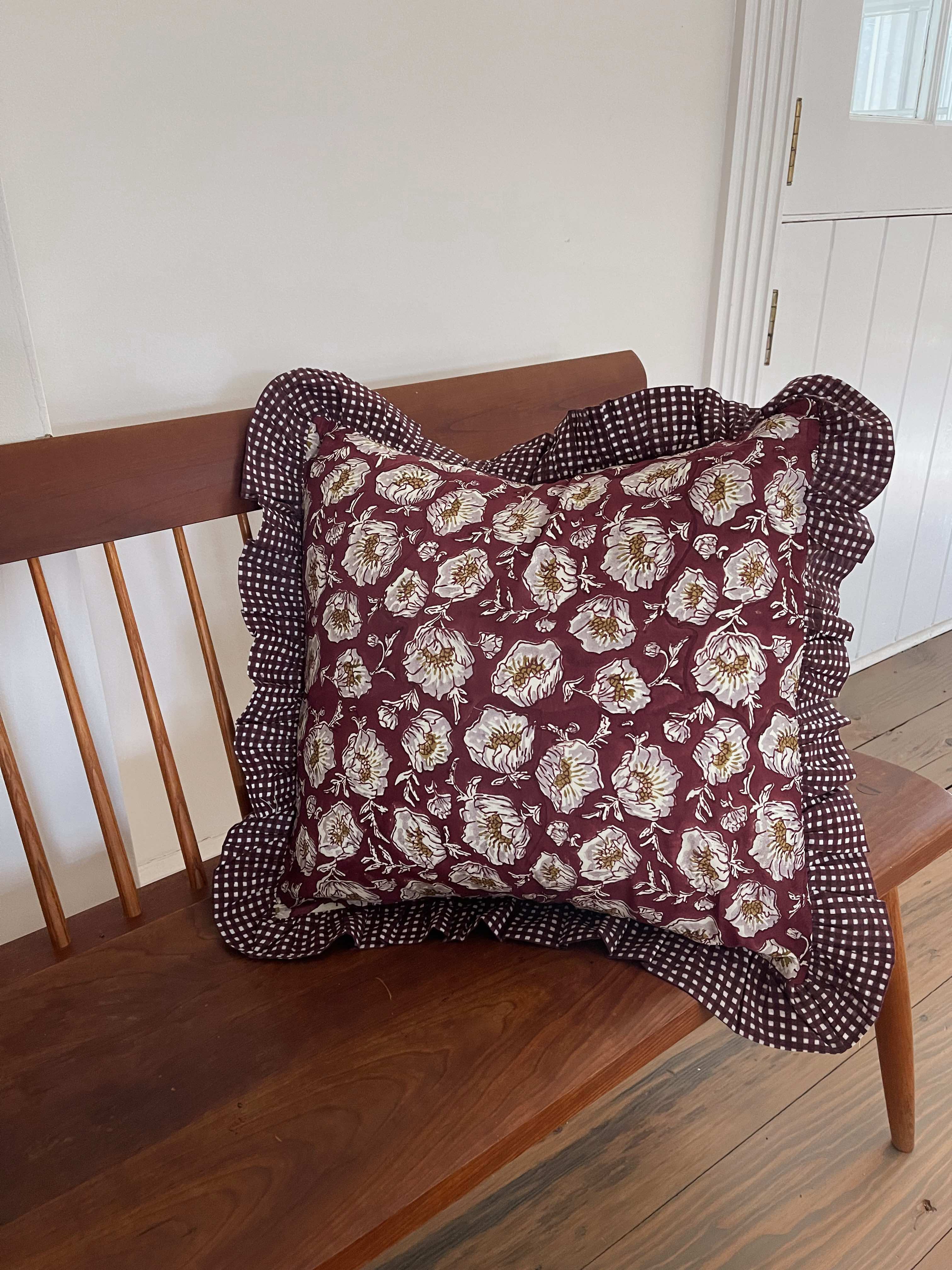 Wine wild poppy floral throw pillow cover with ruffled edges on a couch