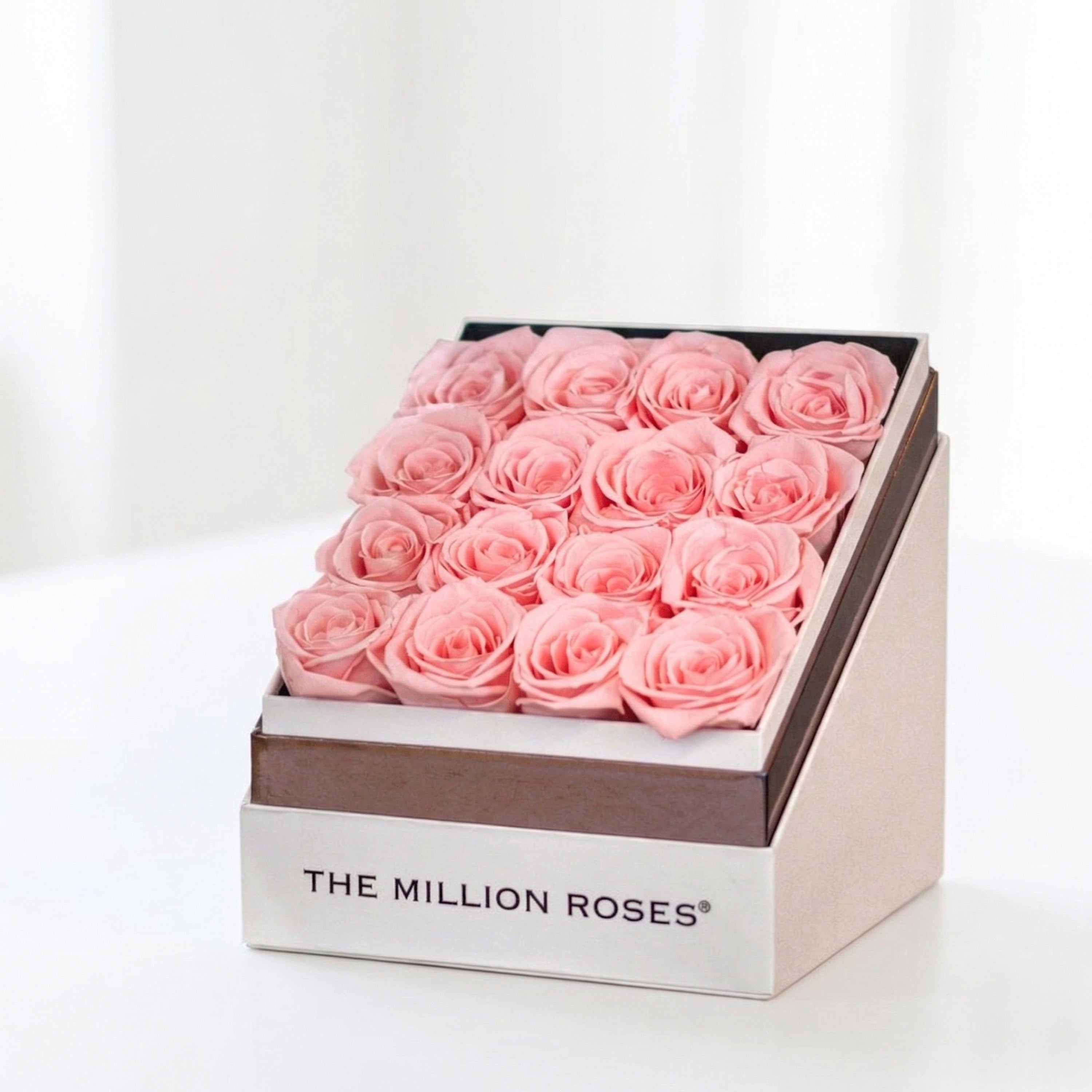 Square white box filled with 16 light pink roses, displayed elegantly