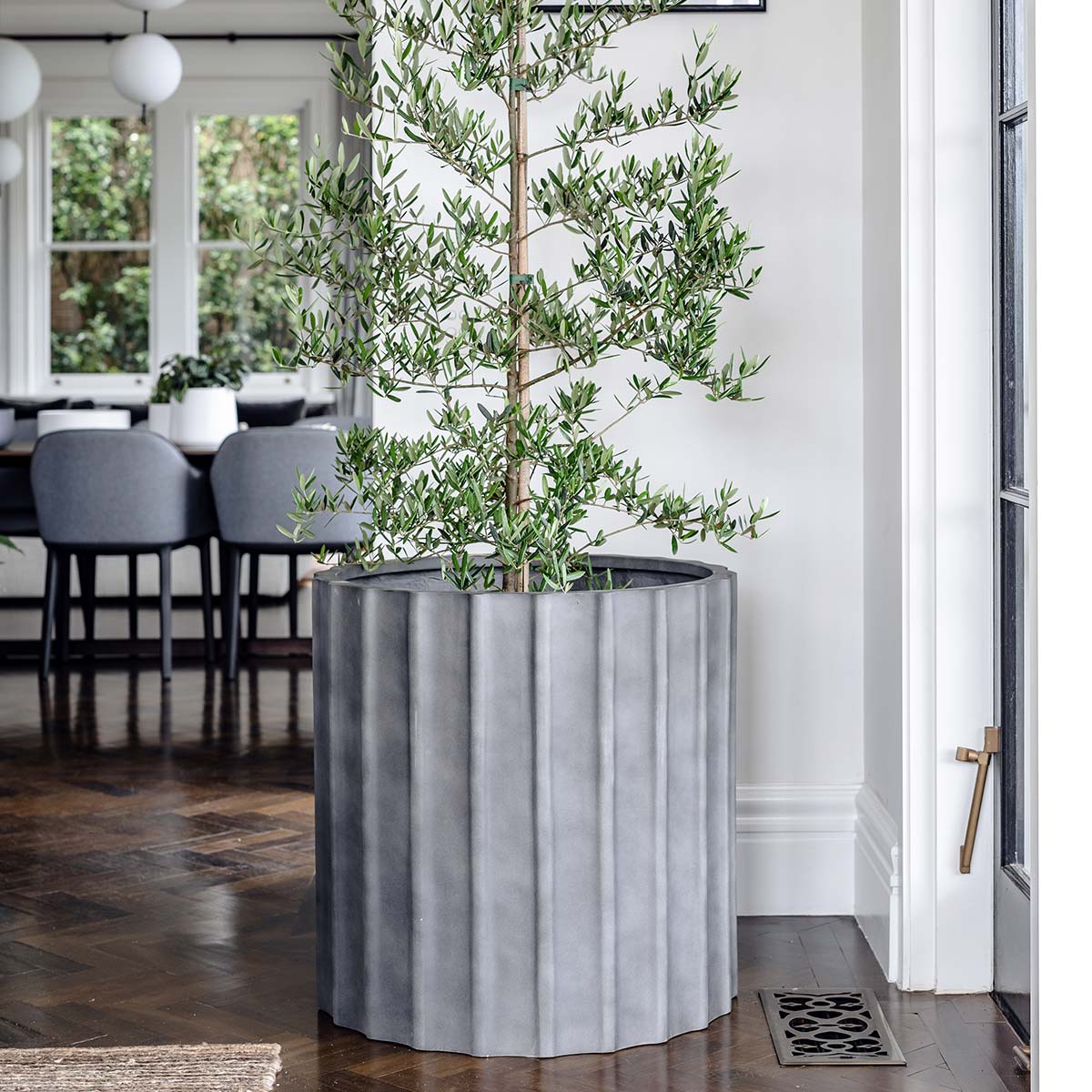 Ripple planter in white with wavy textured surface, cylindrical shape on light floor