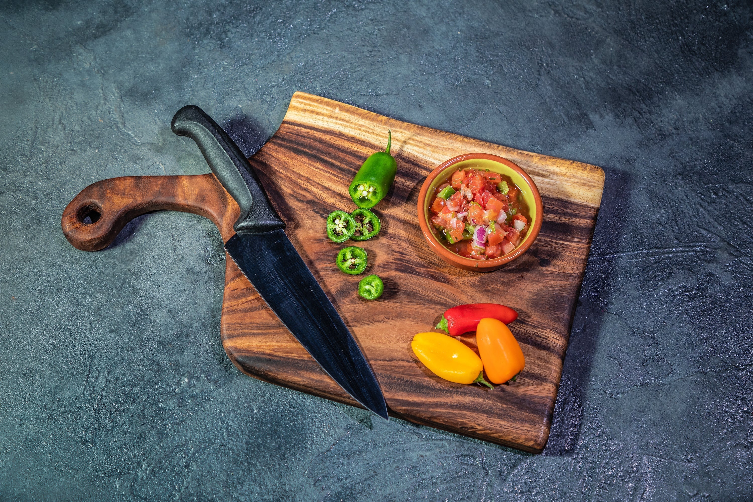 Large live edge handled cutting board in use with sliced food