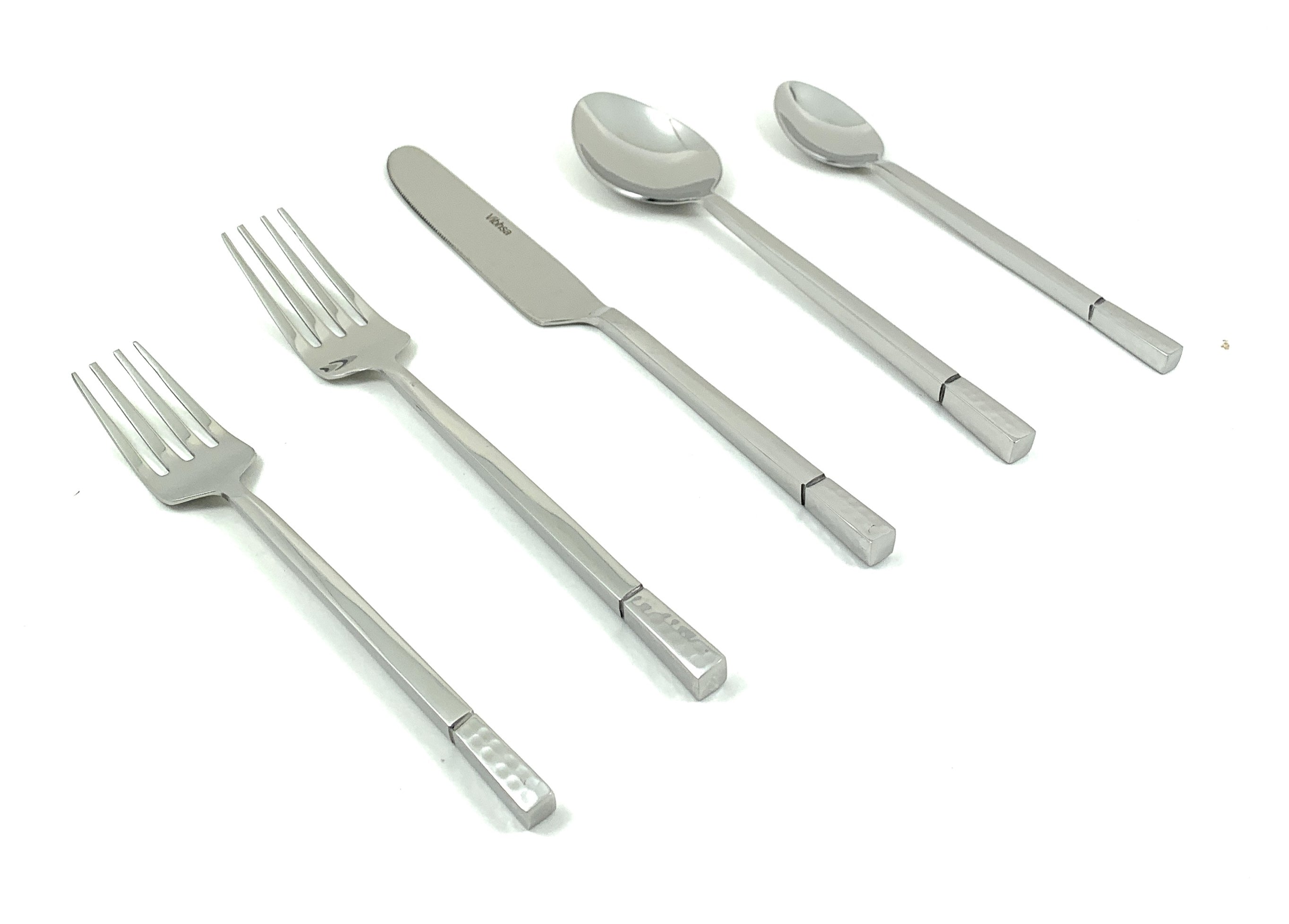 Modern silver flatware set with hammered edges arranged on a dining table